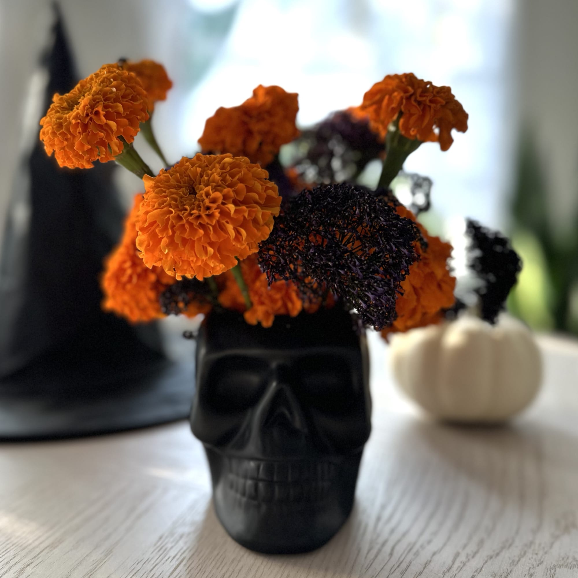 Orange marigolds in a black skull vase on a table