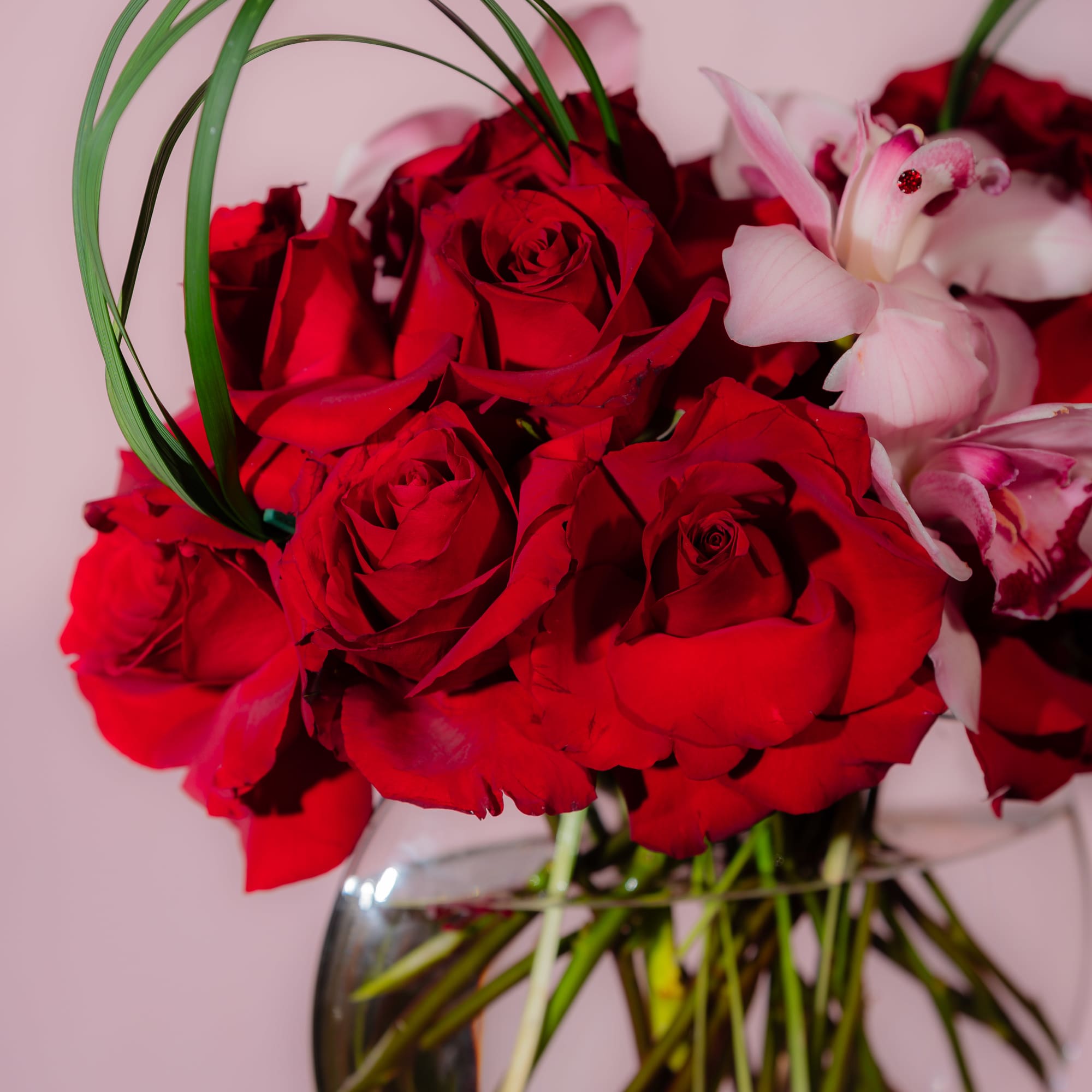 Red roses and pink lilies arranged in a clear glass vase