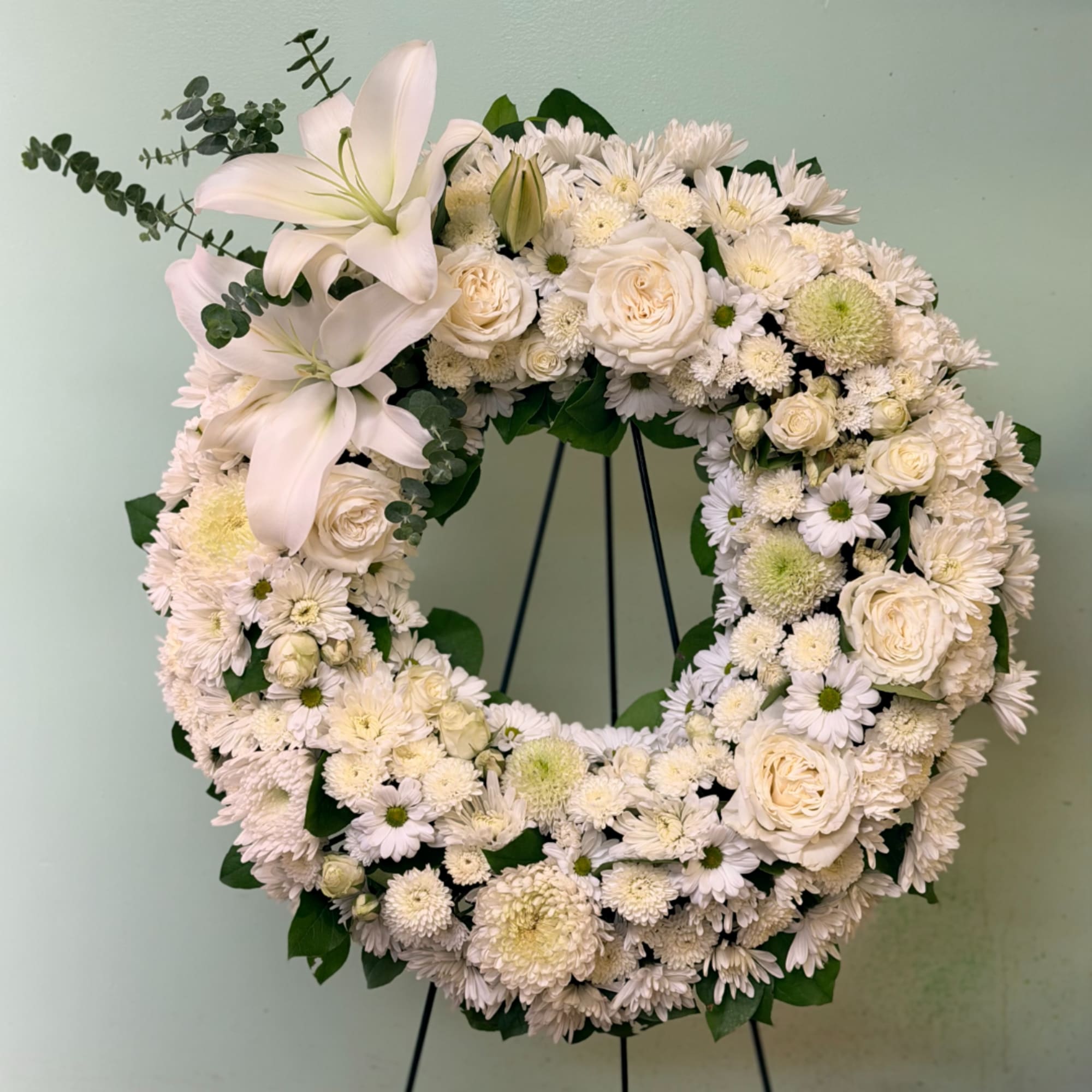 White floral wreath with lilies, roses, and daisies on a stand, photo 3 of 3