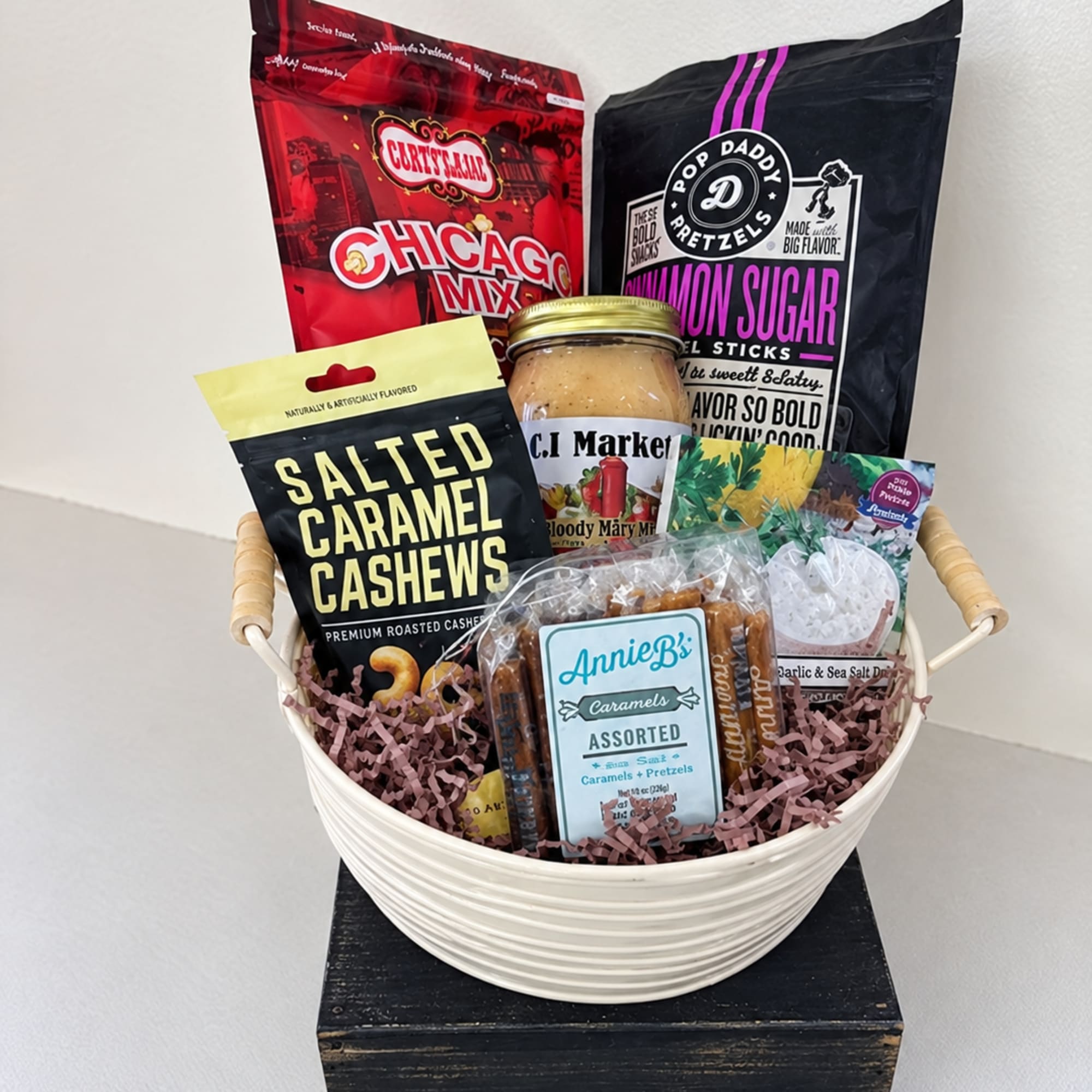Gift basket with assorted snack bags and a jar in a white bowl