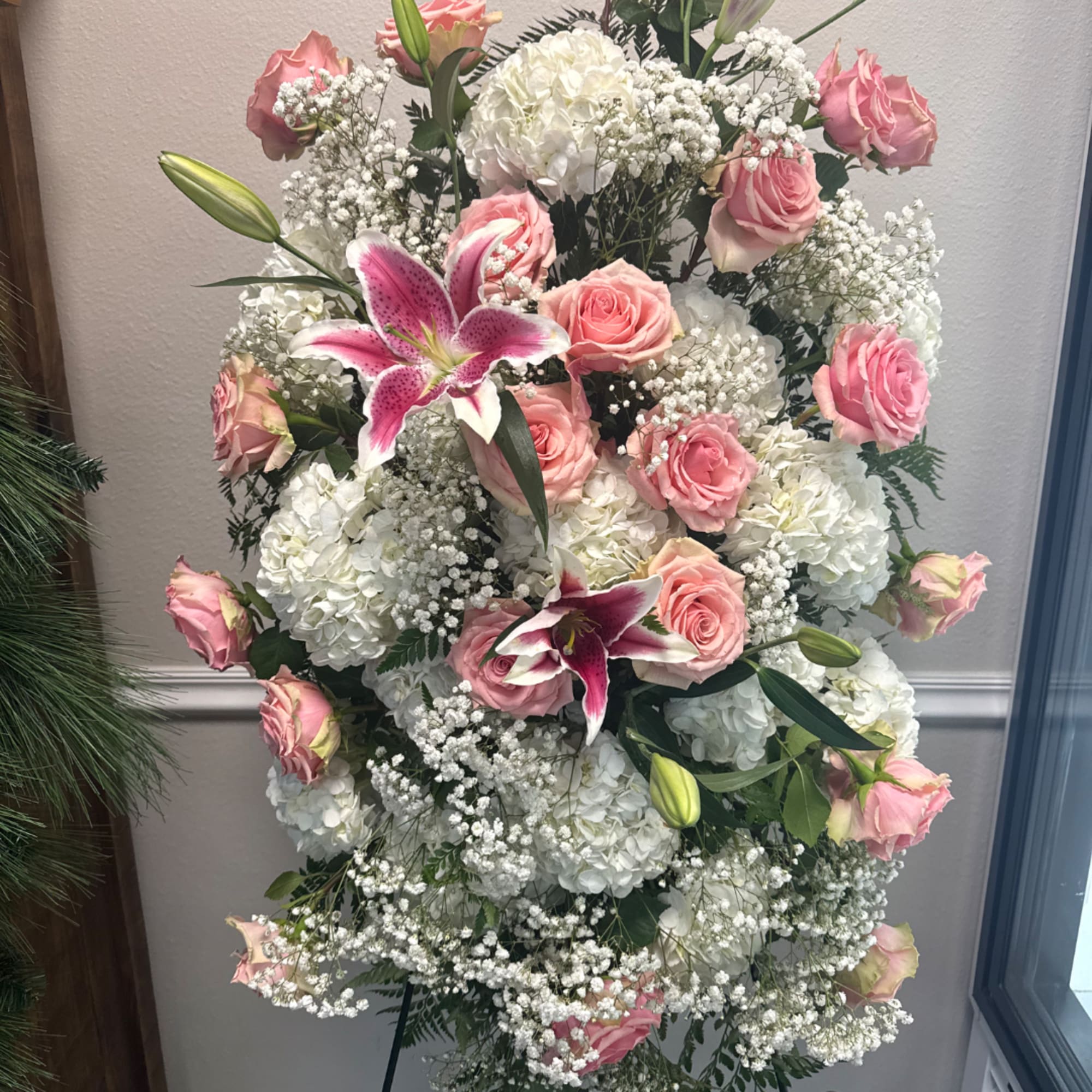 Pink roses and white lilies arranged with white hydrangeas in a standing spray