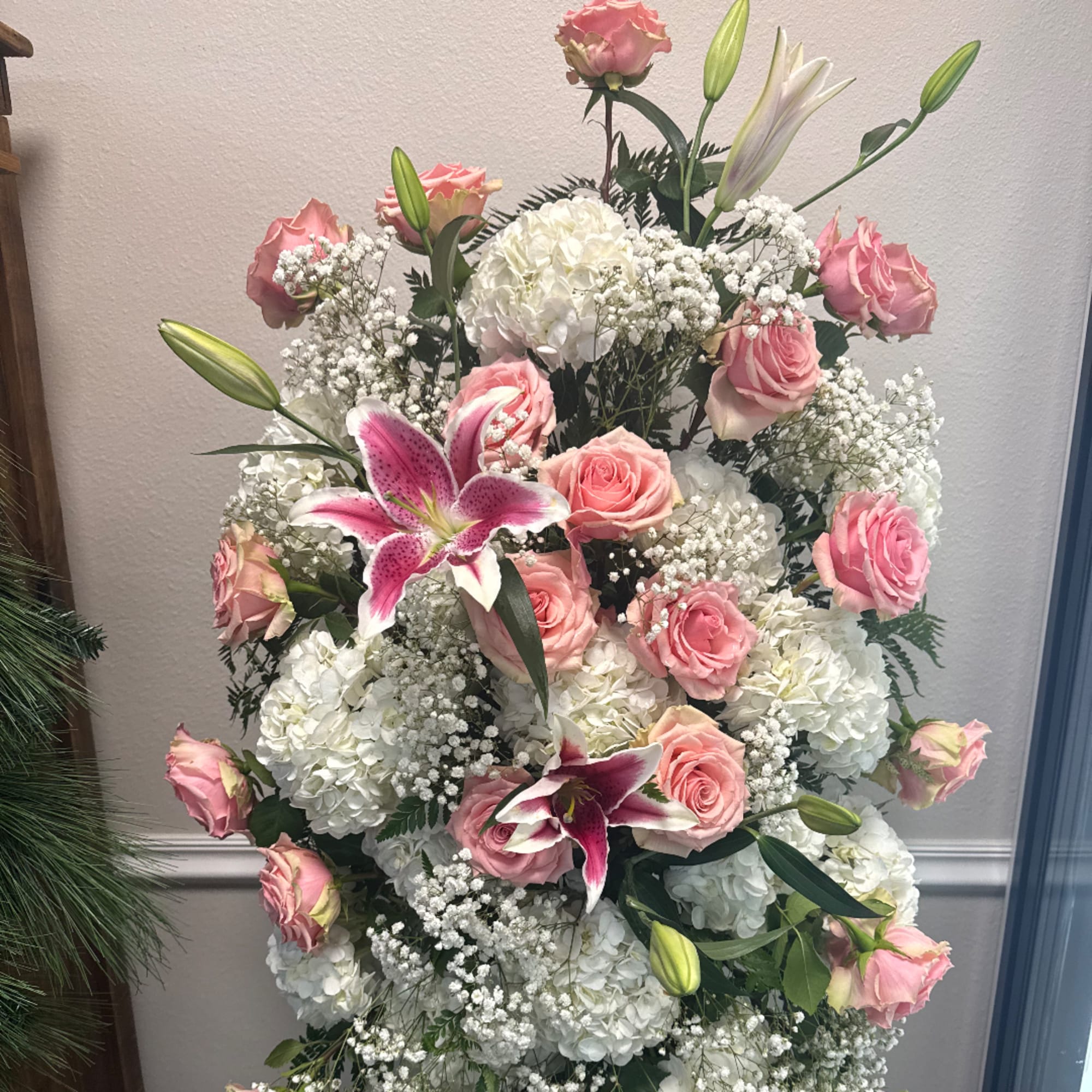 Pink roses and white lilies arranged with white hydrangeas in a tall display