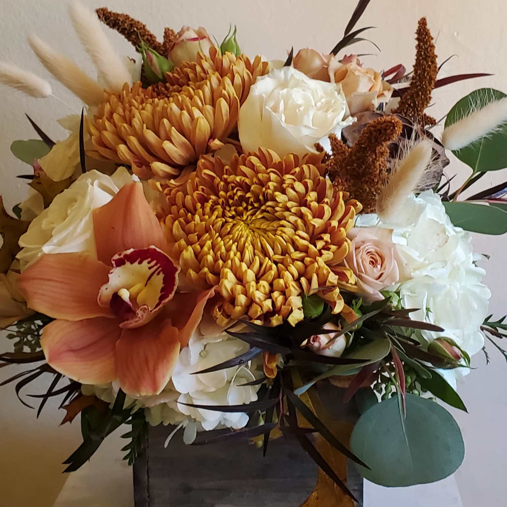 Autumn bouquet with orange chrysanthemums, white roses, and peach orchids in a wooden box