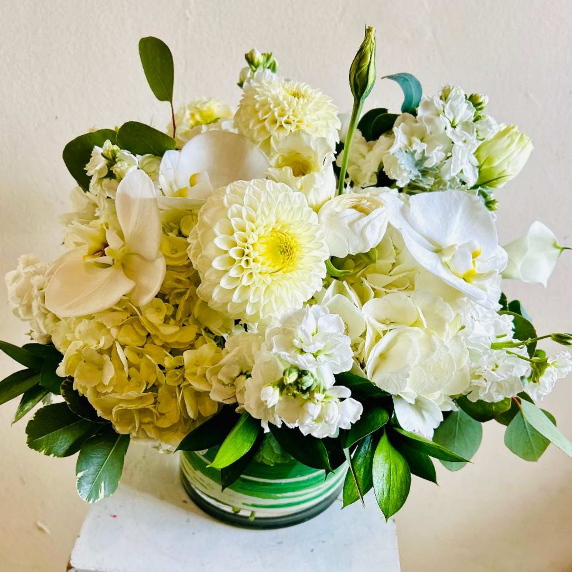 White floral arrangement in a green striped vase