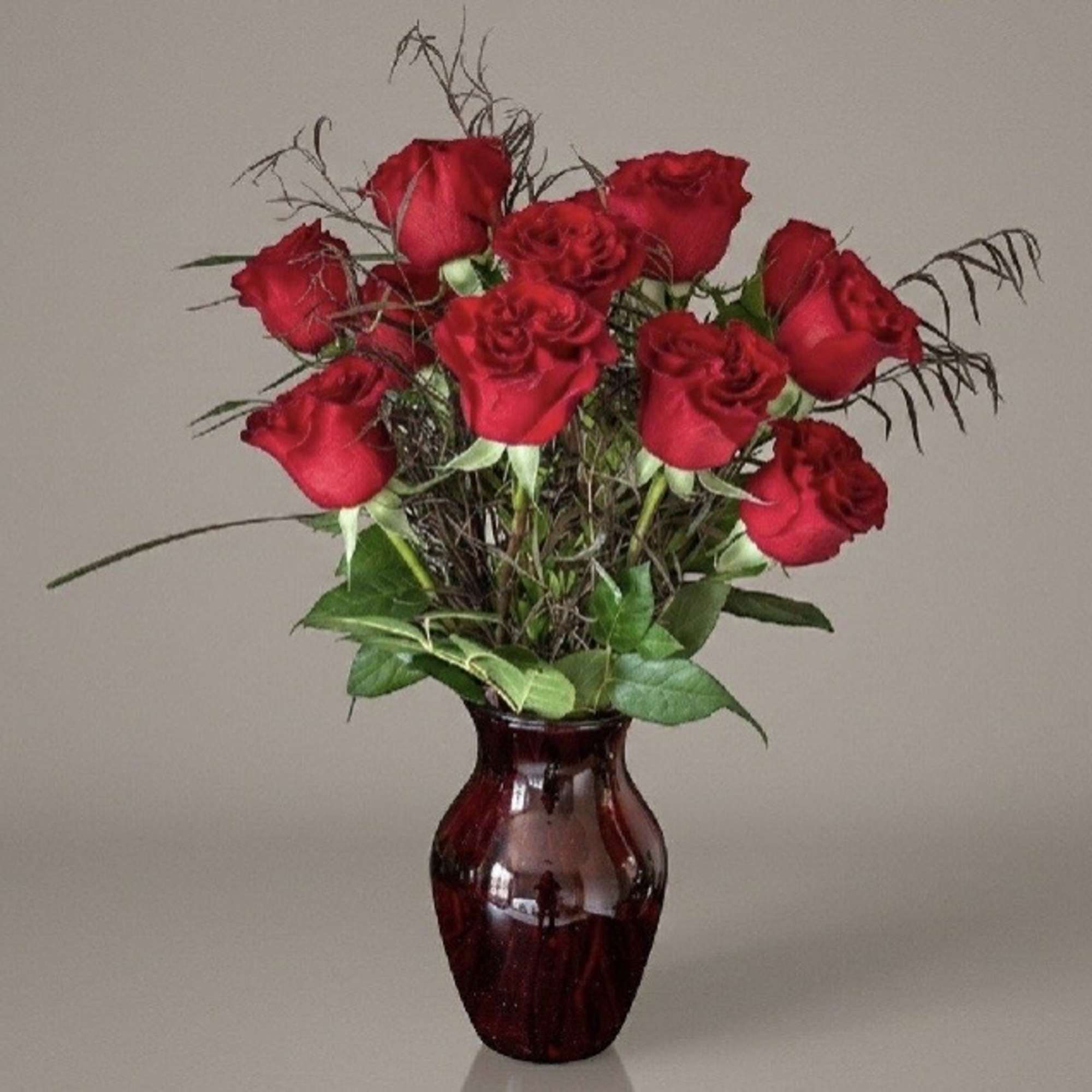 Red roses arranged in a burgundy glass vase