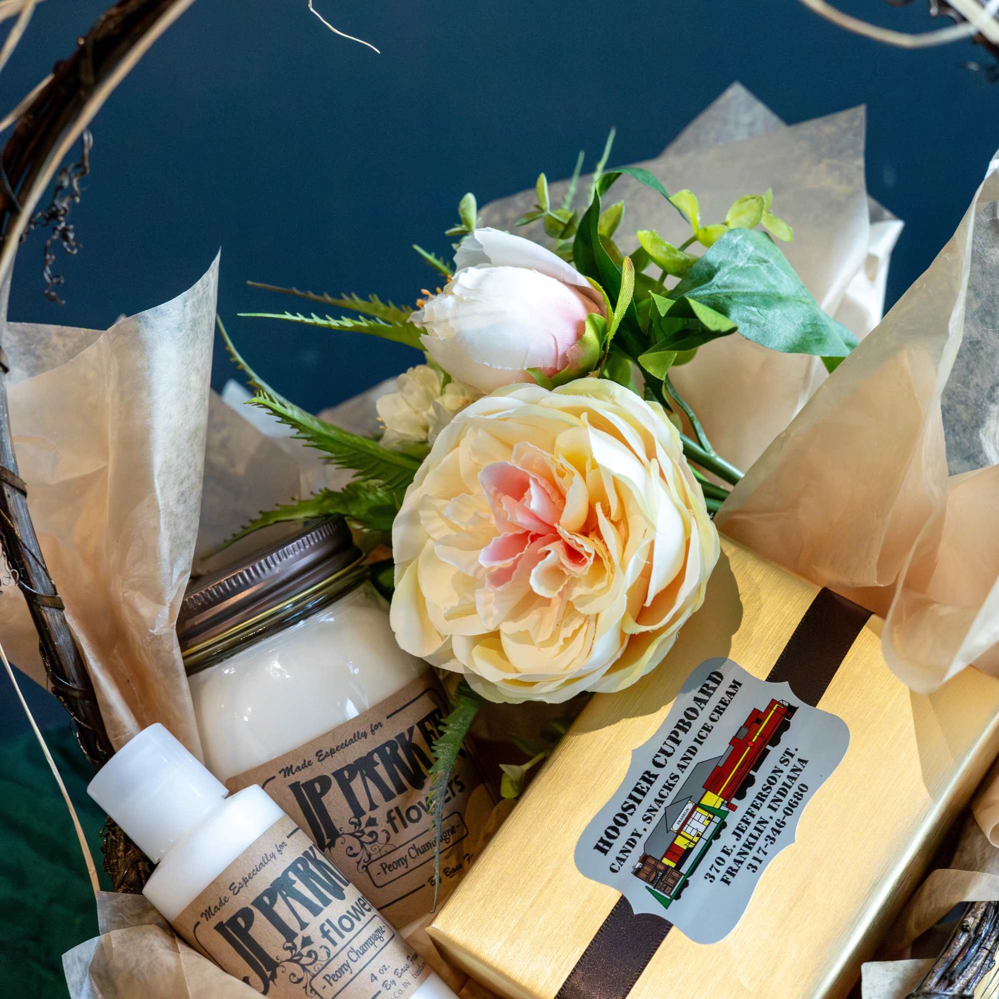 Gift basket with a flower bouquet, candle, and boxed treats