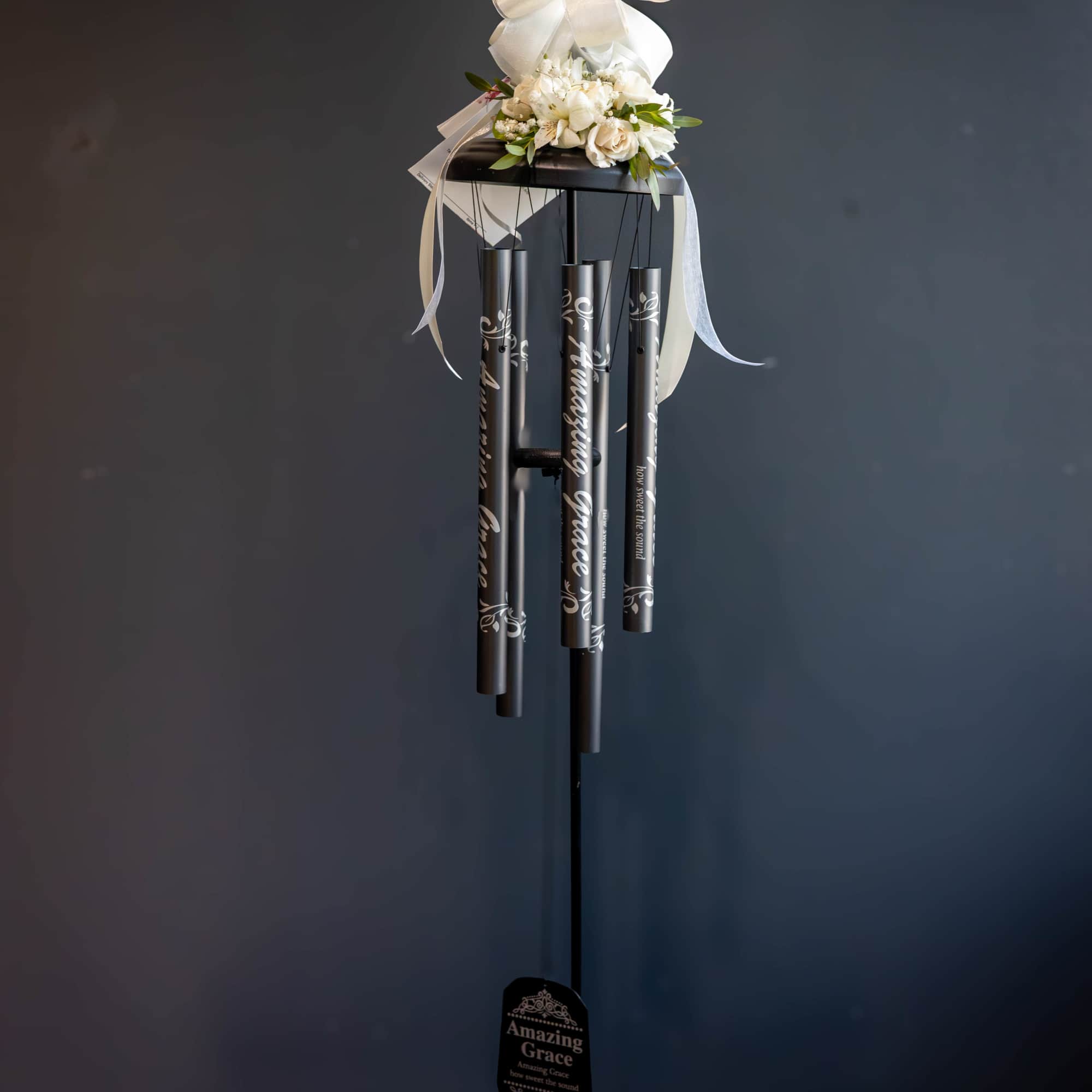 White floral topper with ribbon on a black wind chime stand