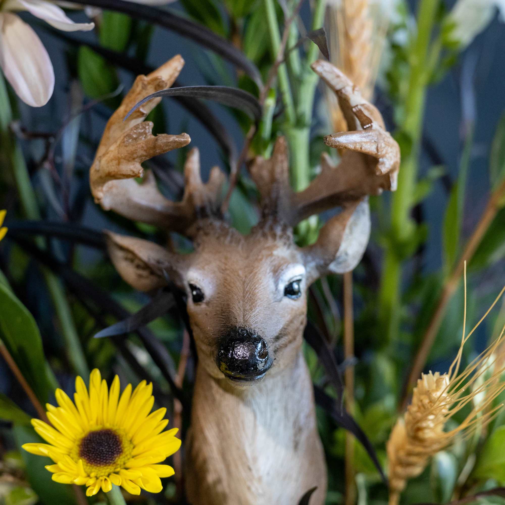 Deer figurine surrounded by yellow daisies and pale flowers