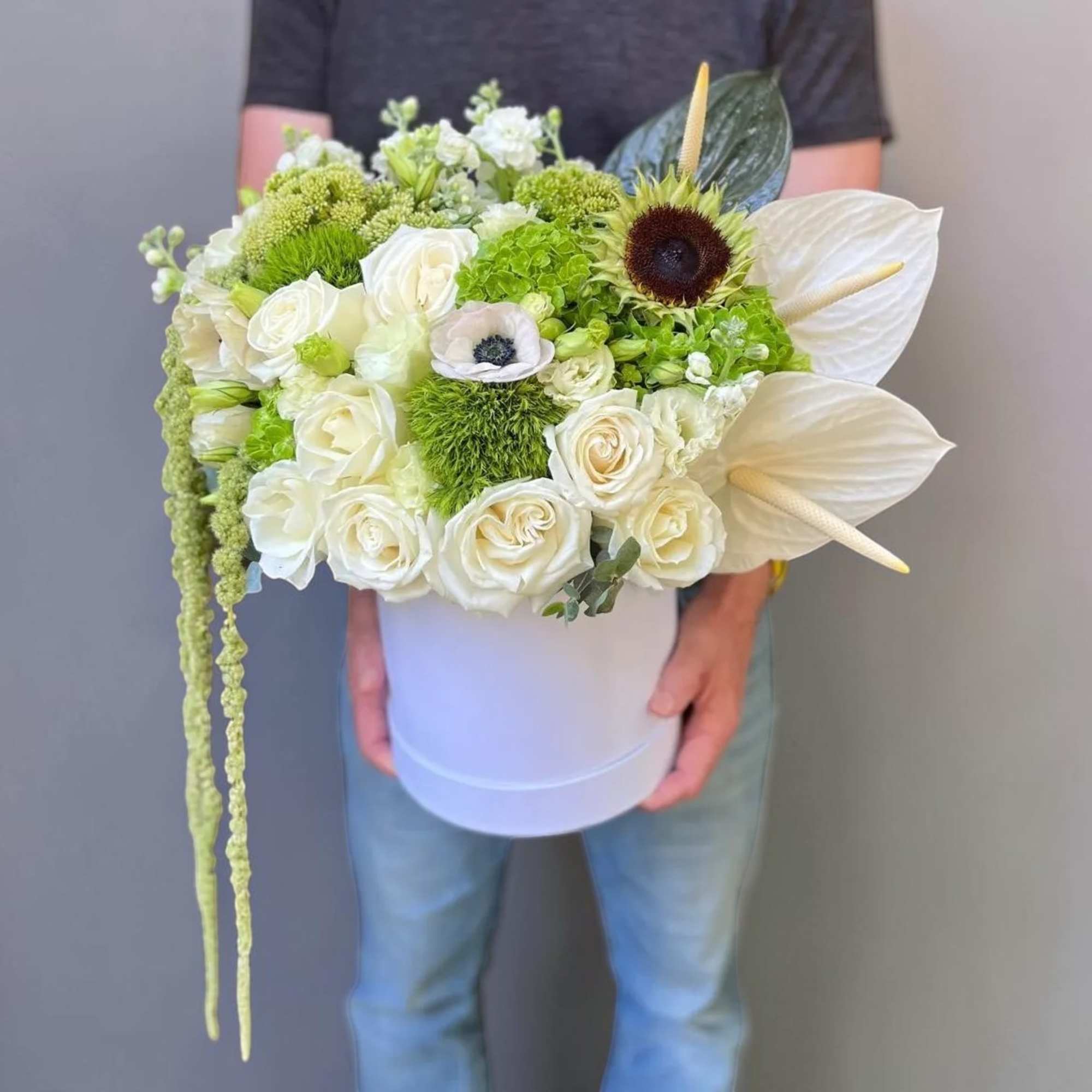 White and green bouquet in a white hatbox with anthuriums and roses