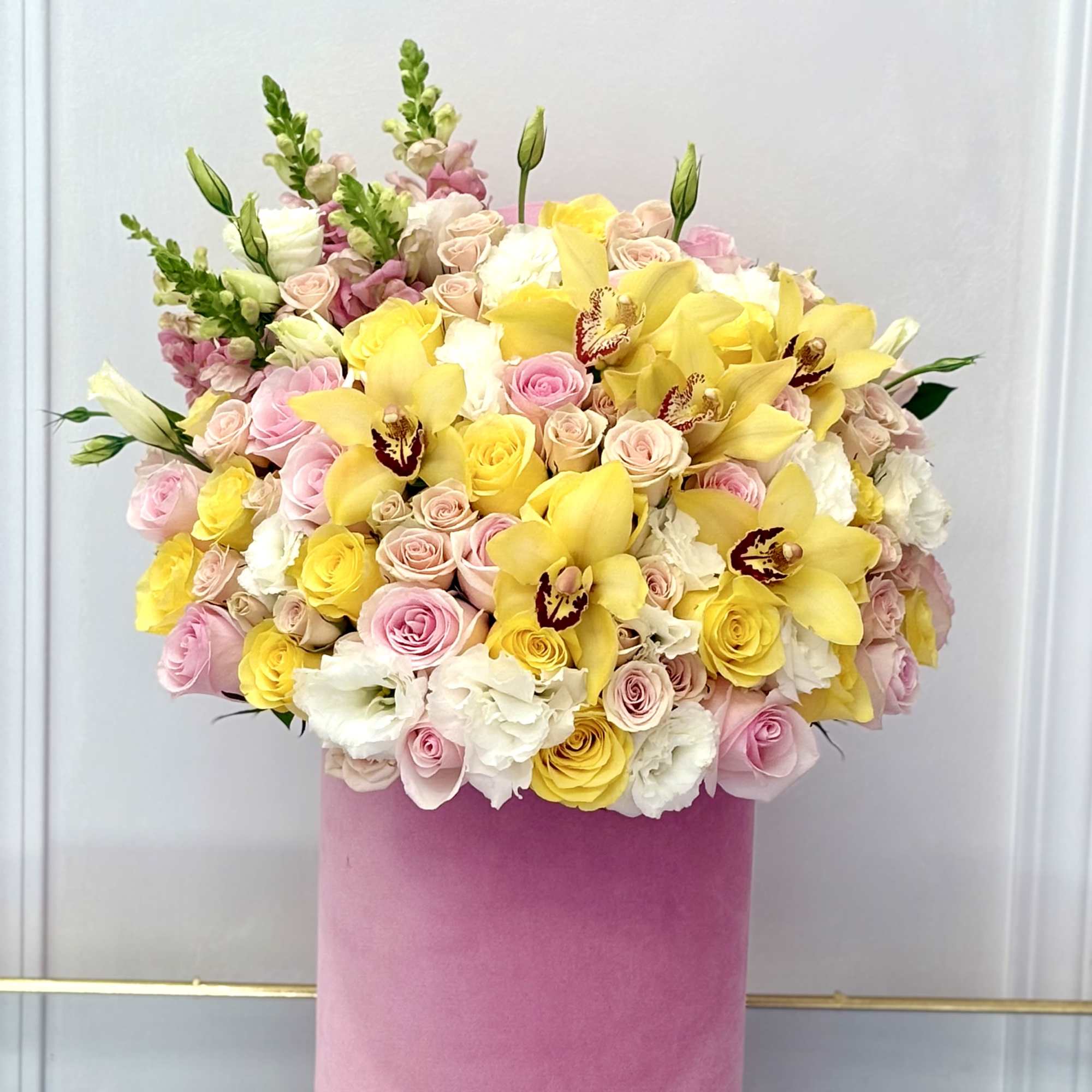 Pink and yellow floral arrangement in a tall pink box