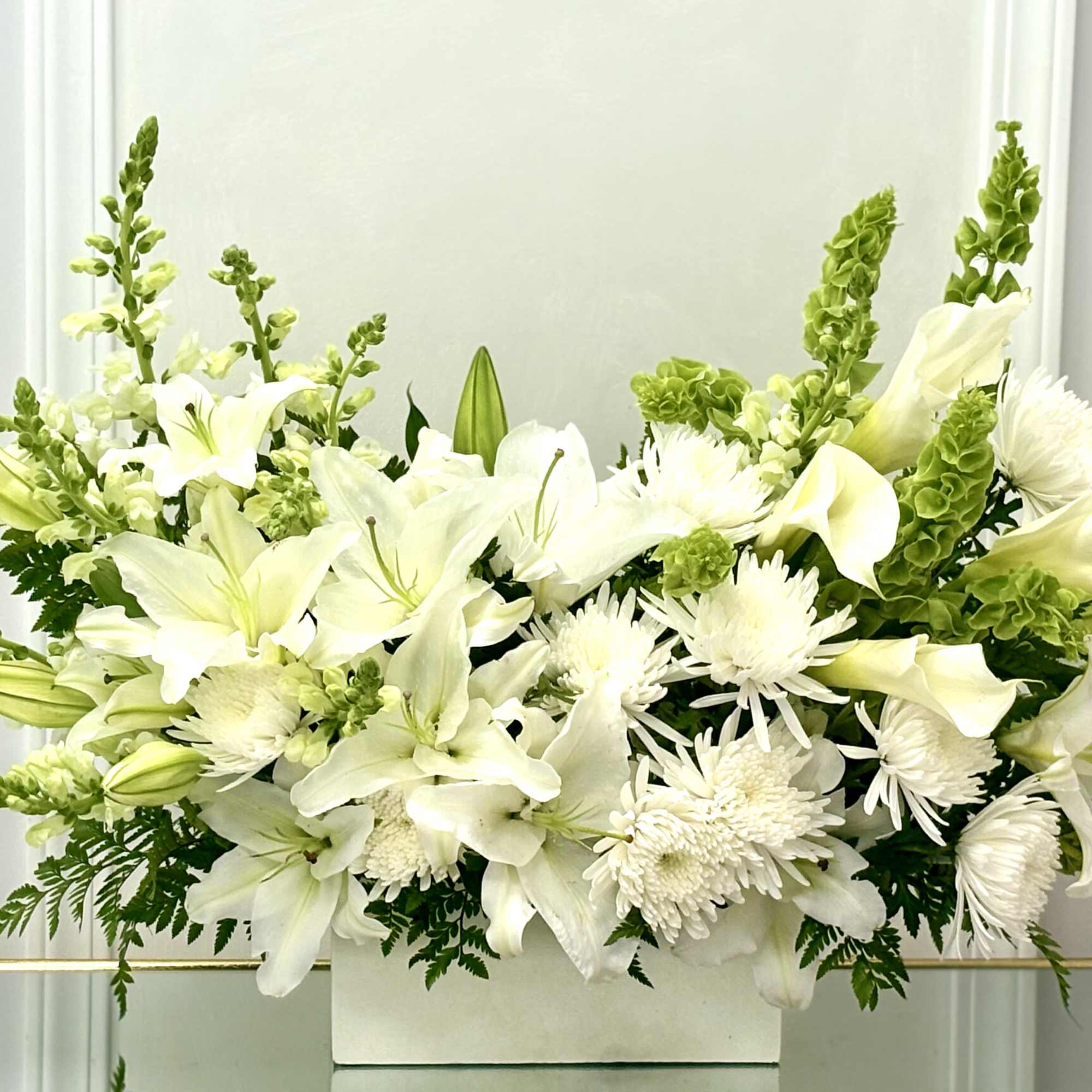 White lilies and chrysanthemums arranged in a rectangular vase