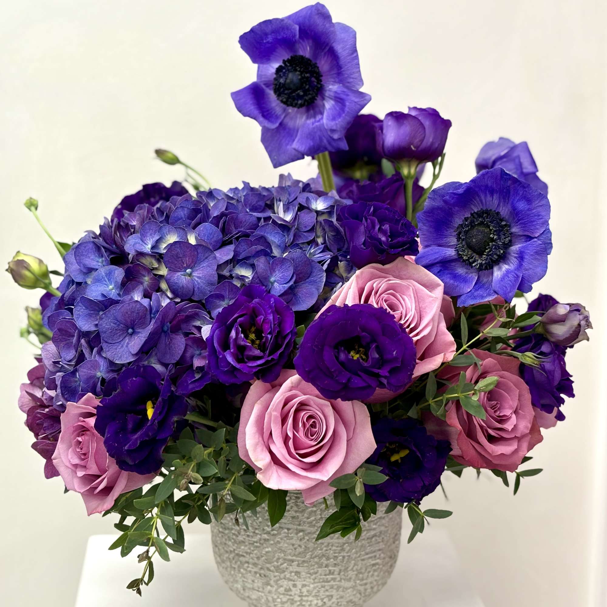Purple and pink floral arrangement in a textured gray vase