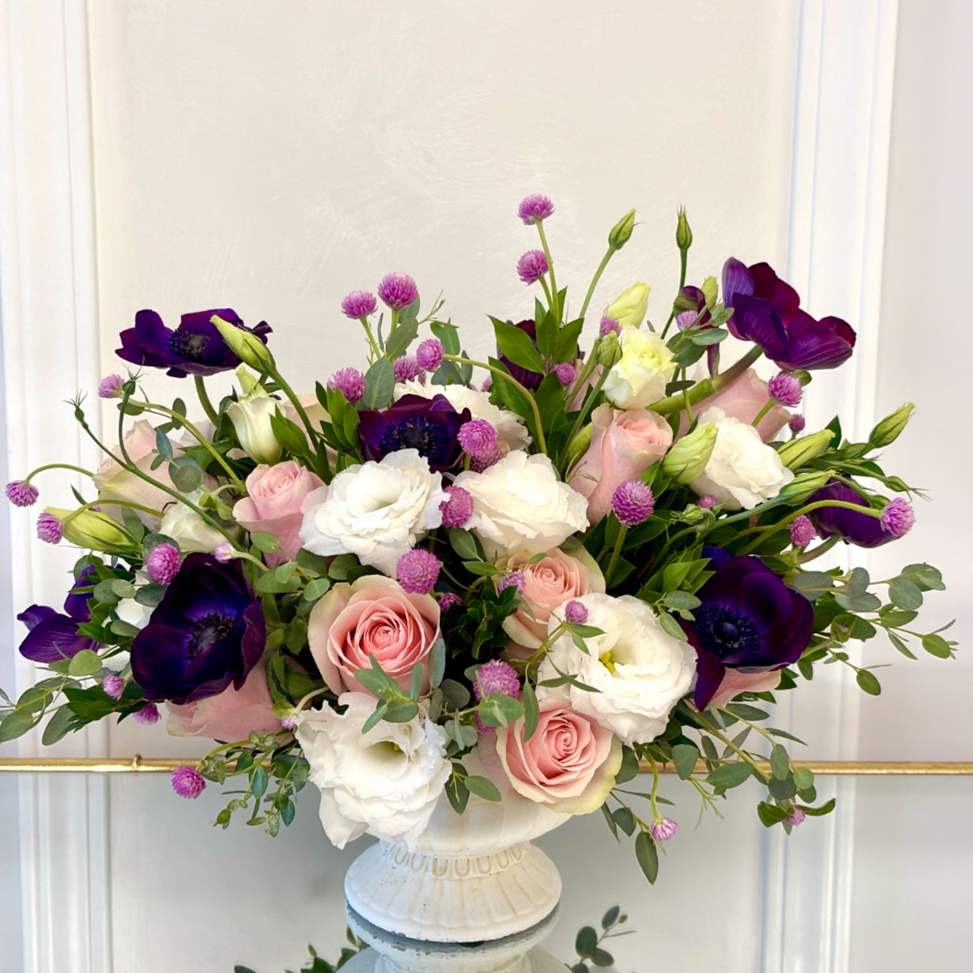 Pink and white roses with purple anemones in a white vase