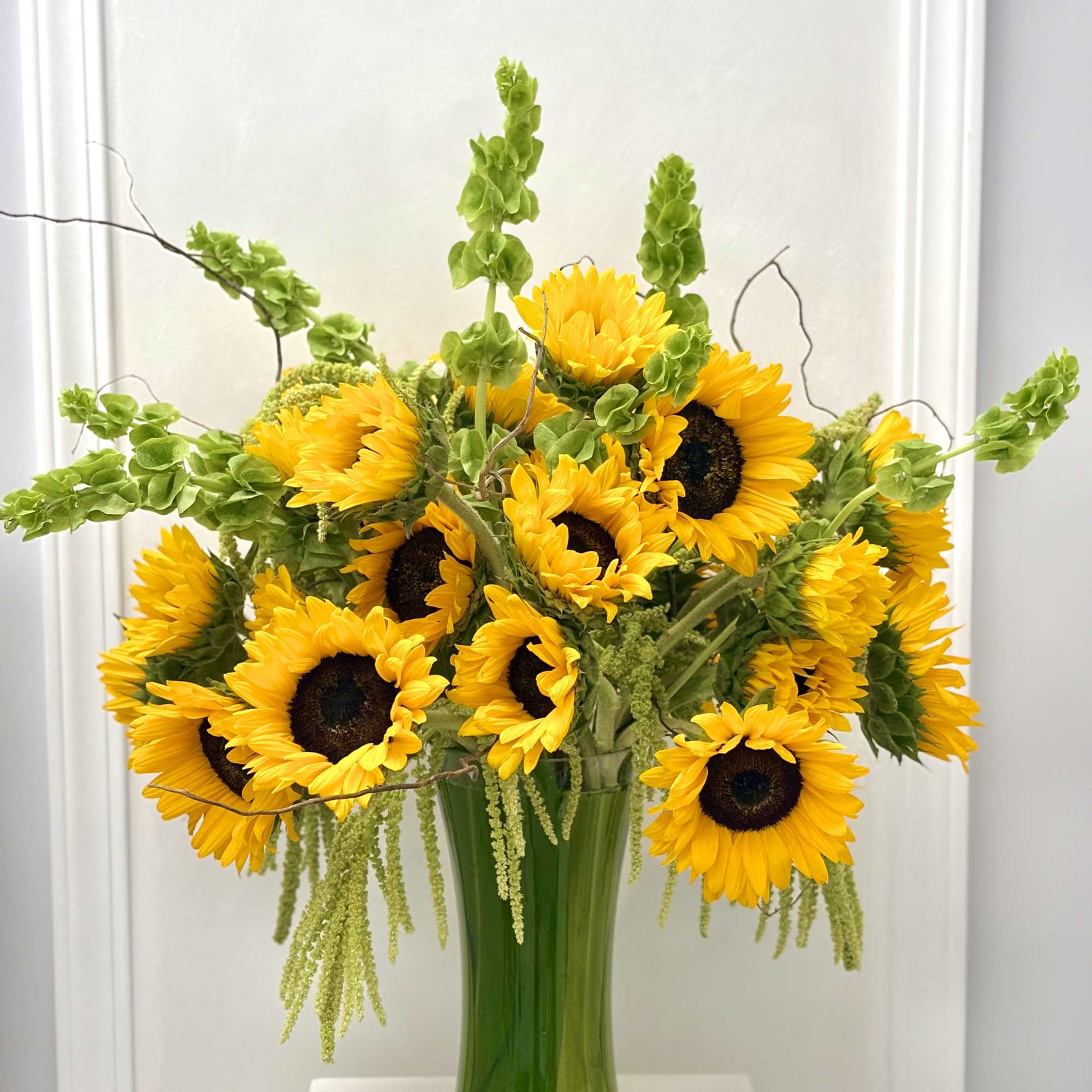 A vibrant, joyful arrangement overflowing with sunny yellow sunflowers, lush green foliage