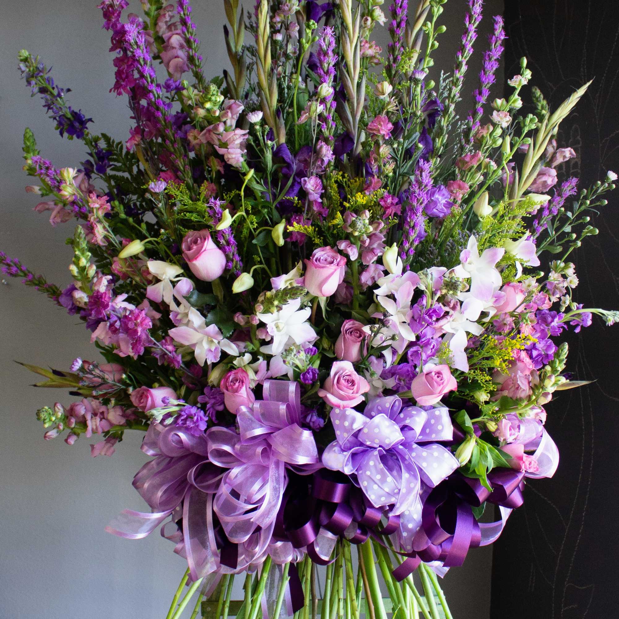 Tall bouquet of pink and purple flowers with ribbon bows