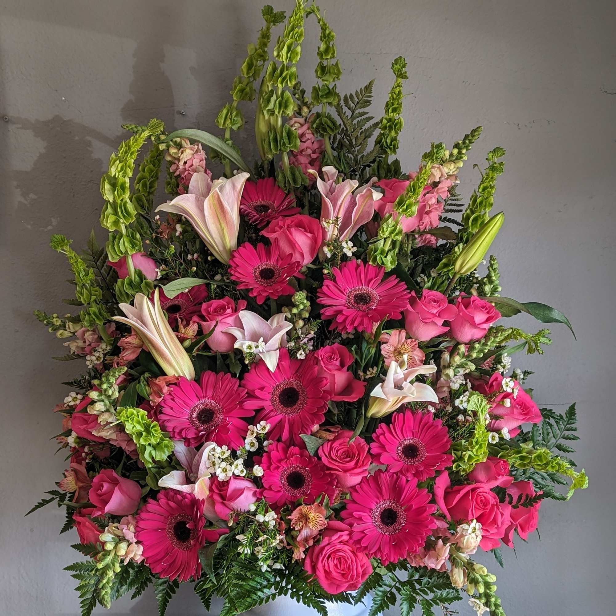 Pink gerbera and rose arrangement in a white pedestal vase