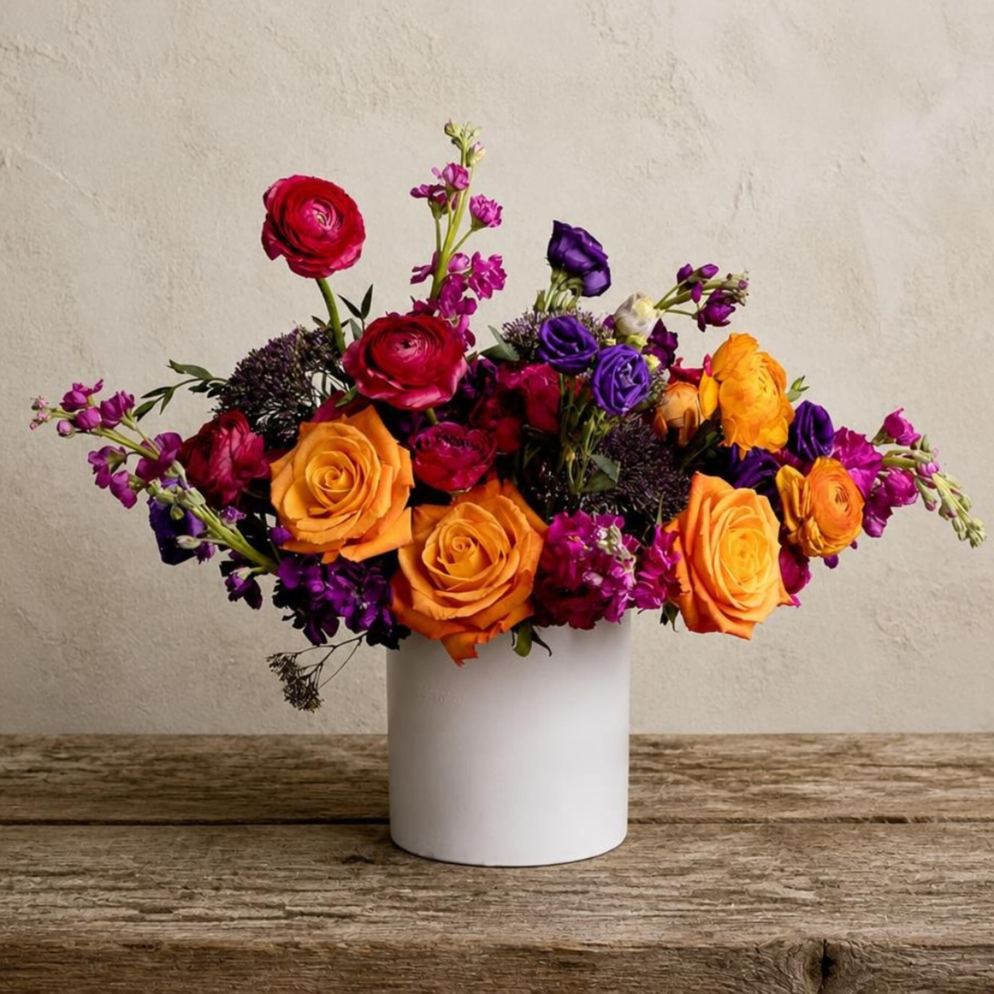 Colorful bouquet of roses and purple flowers in a white vase