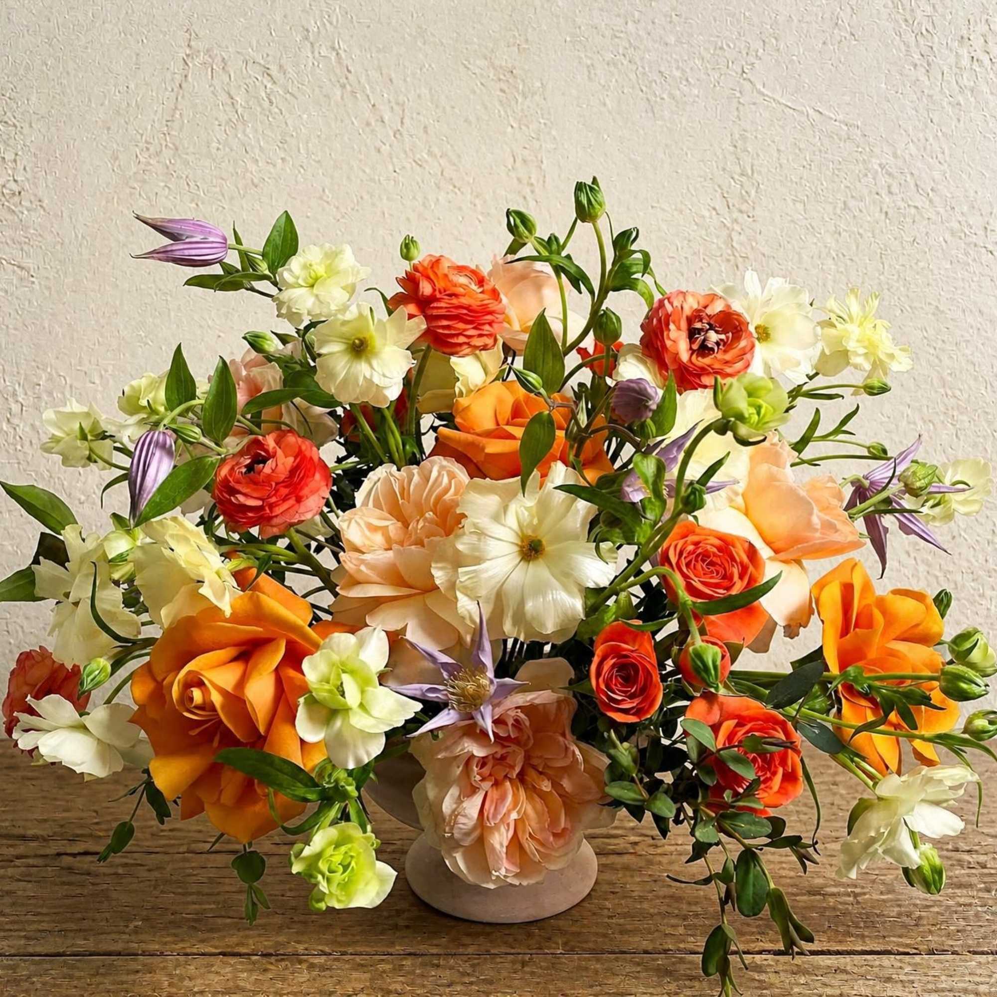 Orange and cream floral arrangement in a low vase