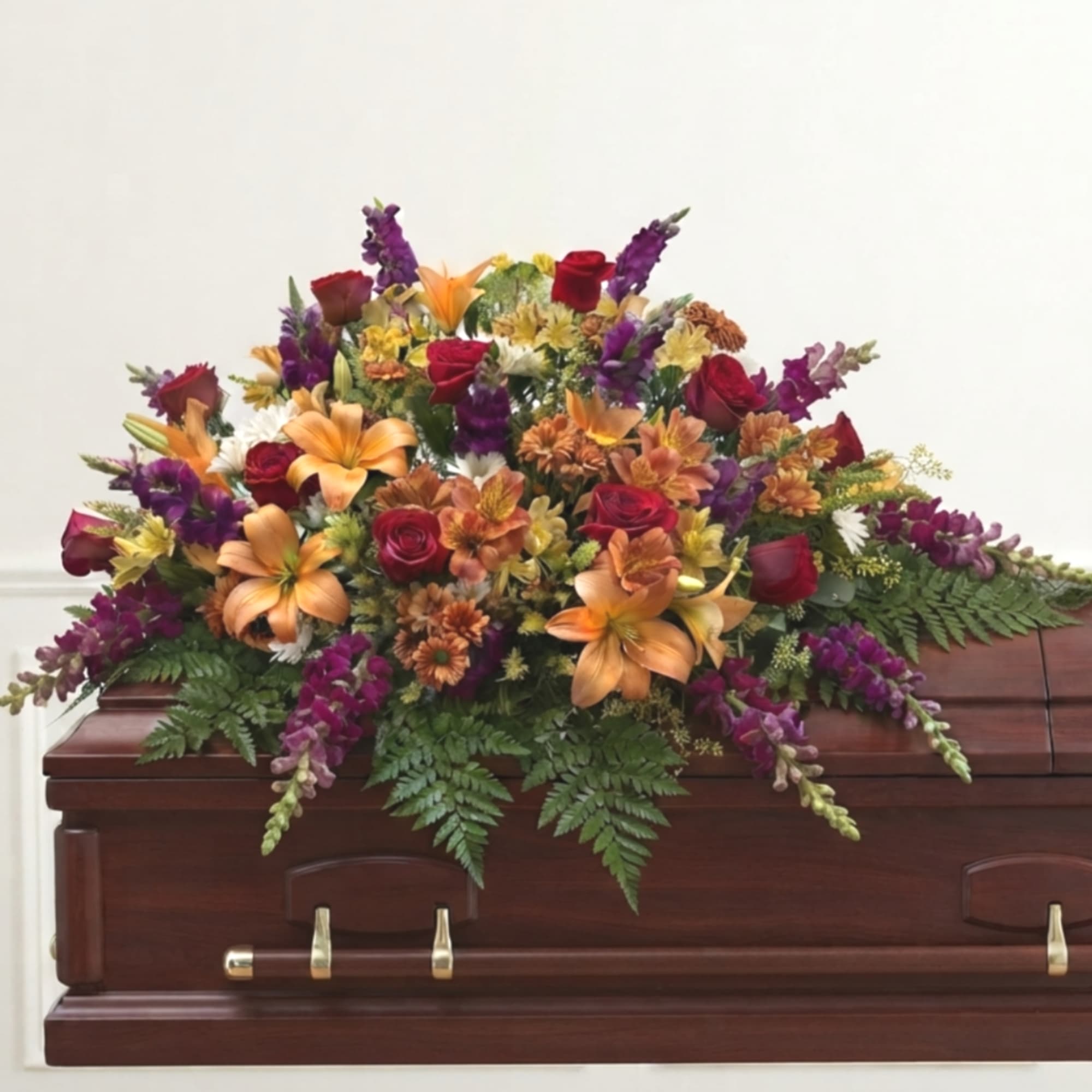 Colorful floral spray on a wooden casket with roses and lilies