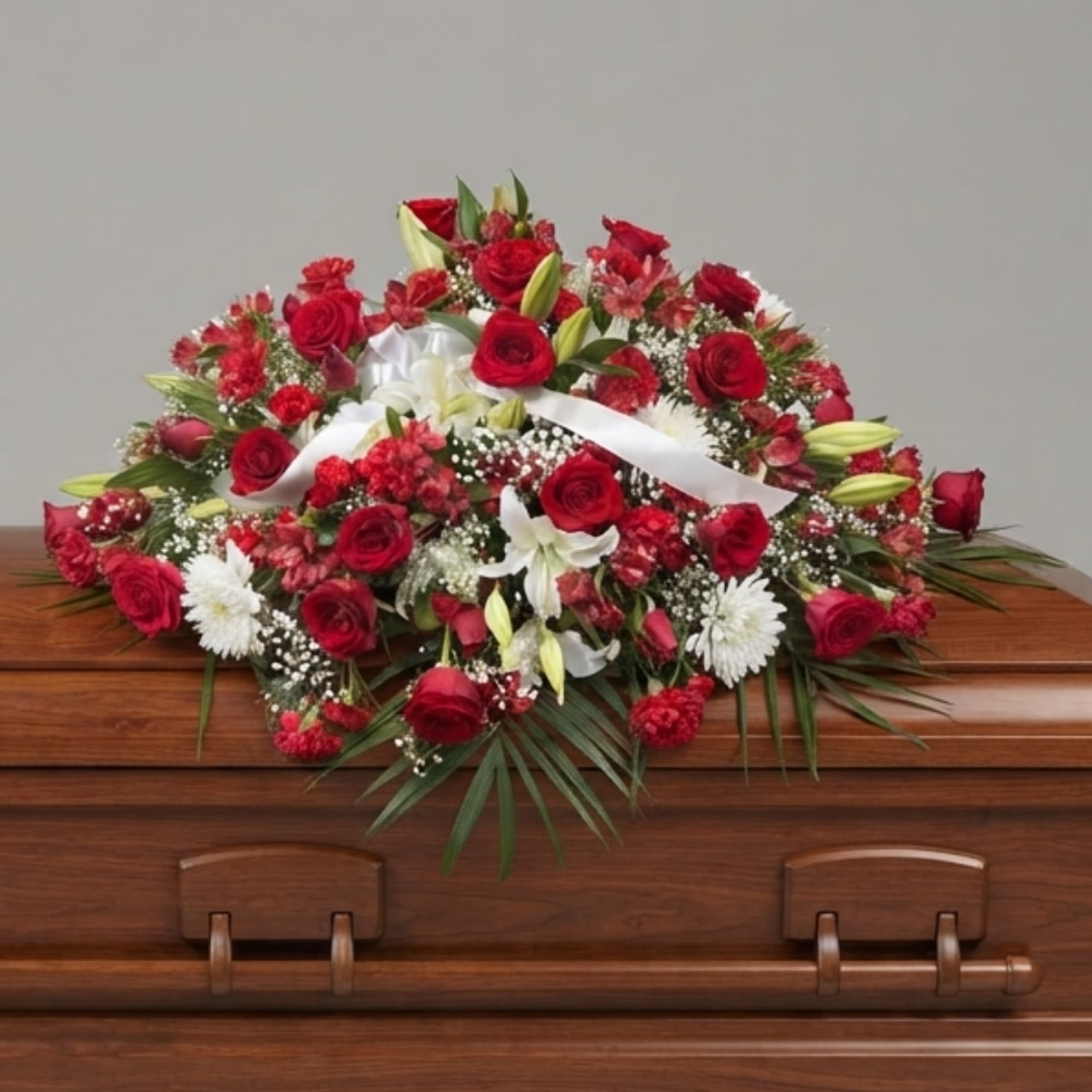 Red and white floral casket spray with ribbon