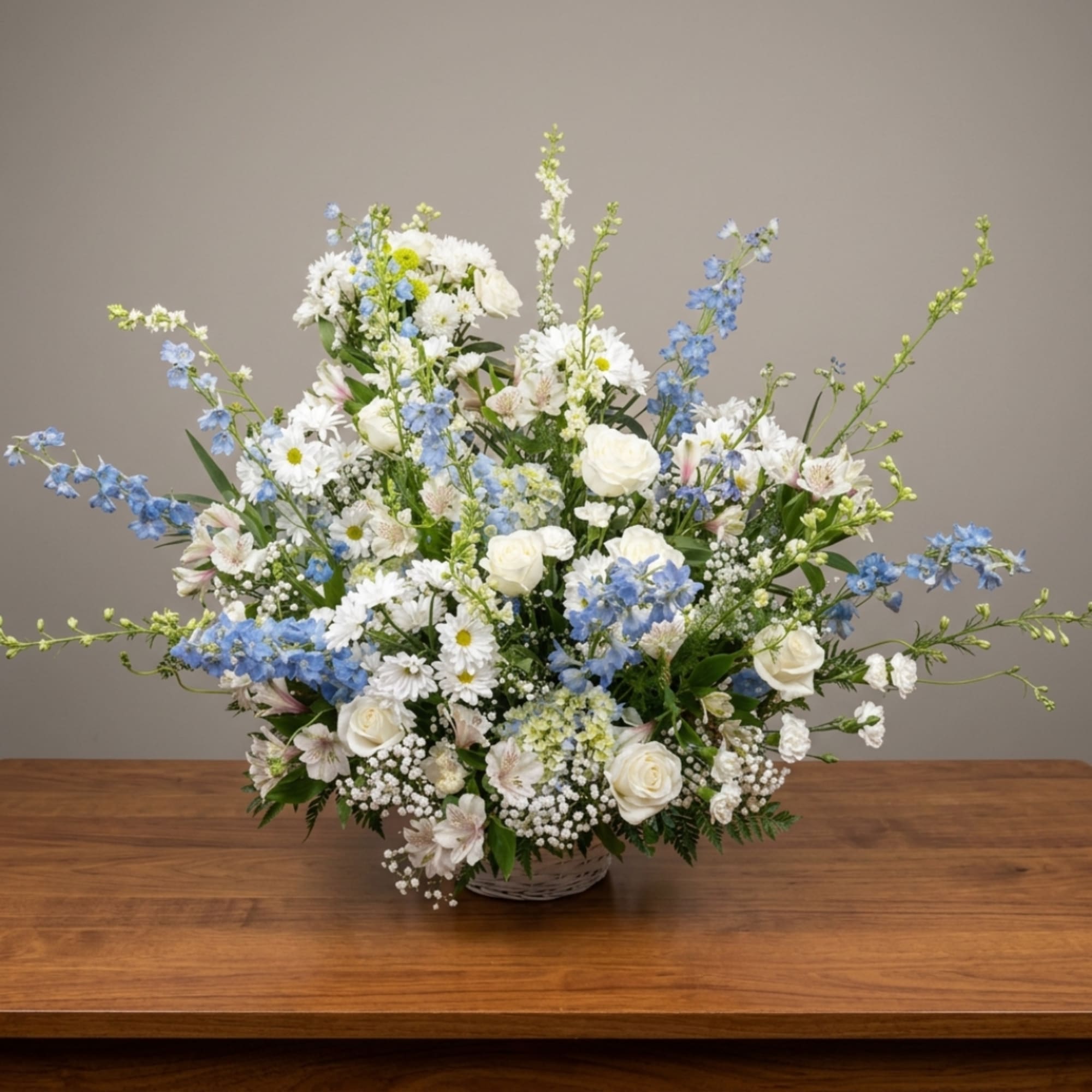 White and blue mixed flower arrangement in a basket vase