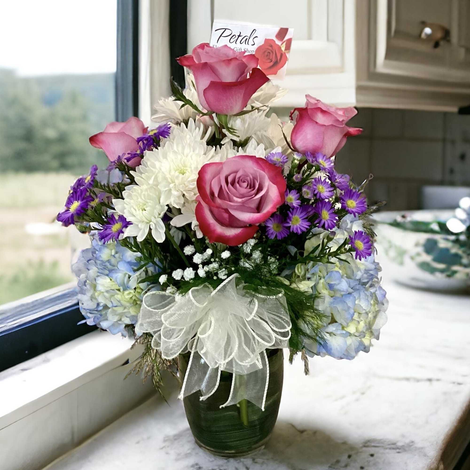 Pink roses and white chrysanthemums in a glass vase with a ribbon bow