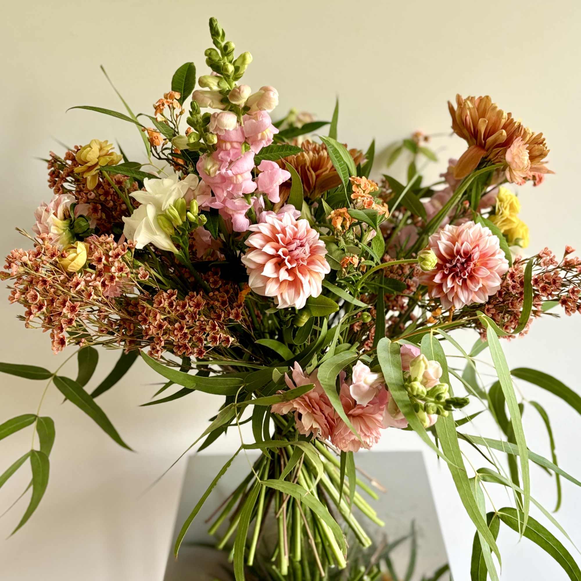 Loose bouquet of pink, peach, and white flowers with long greenery