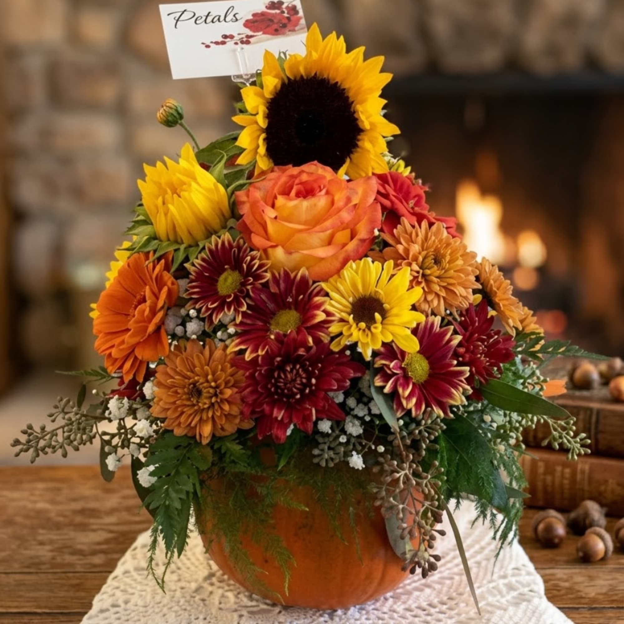 Autumn flower arrangement in a pumpkin-shaped container with sunflowers and mums
