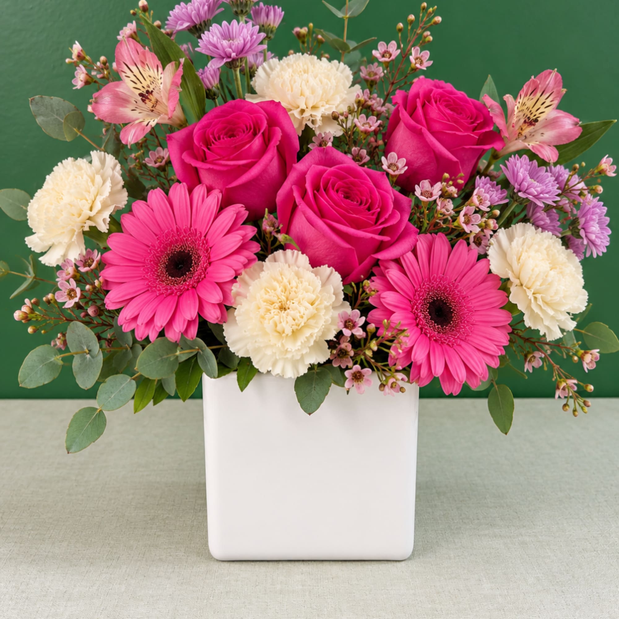 Pink roses and gerbera daisies in a white vase