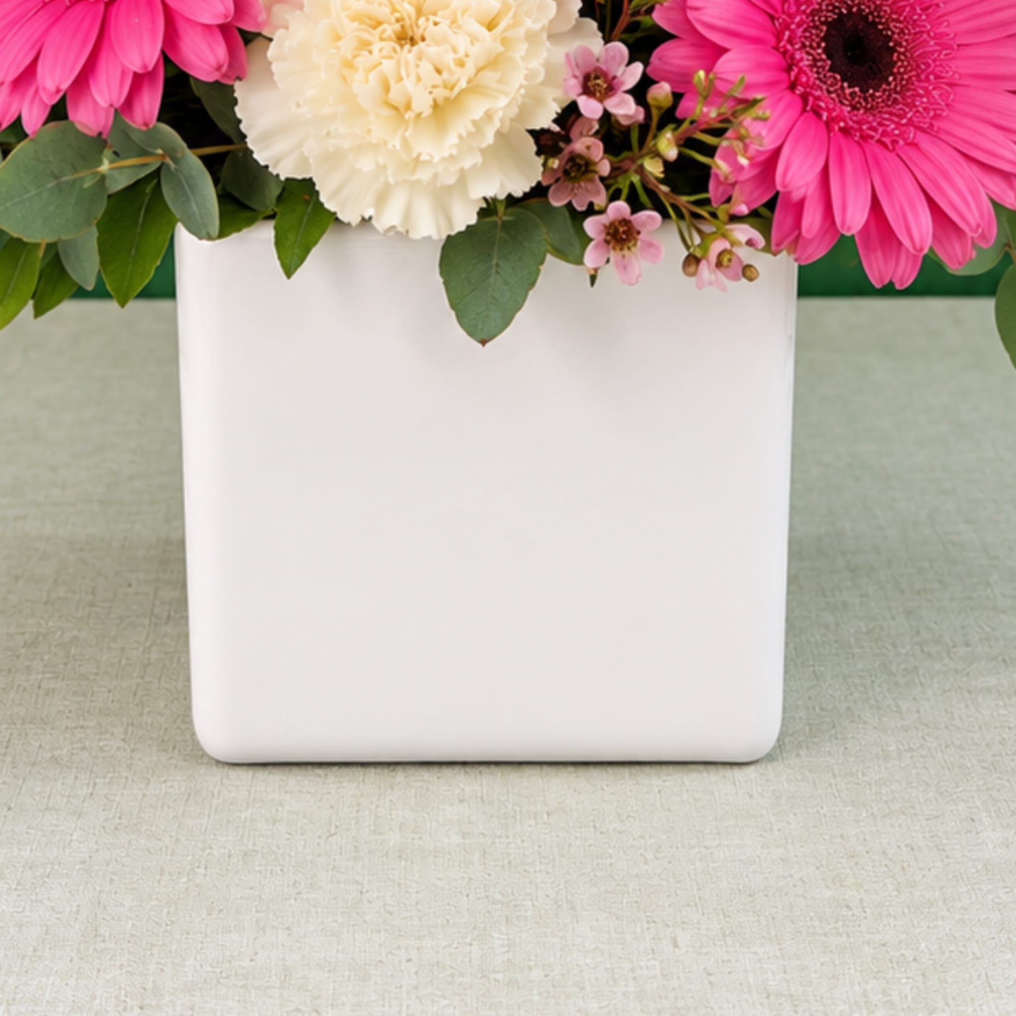 Pink and cream flowers arranged in a white vase