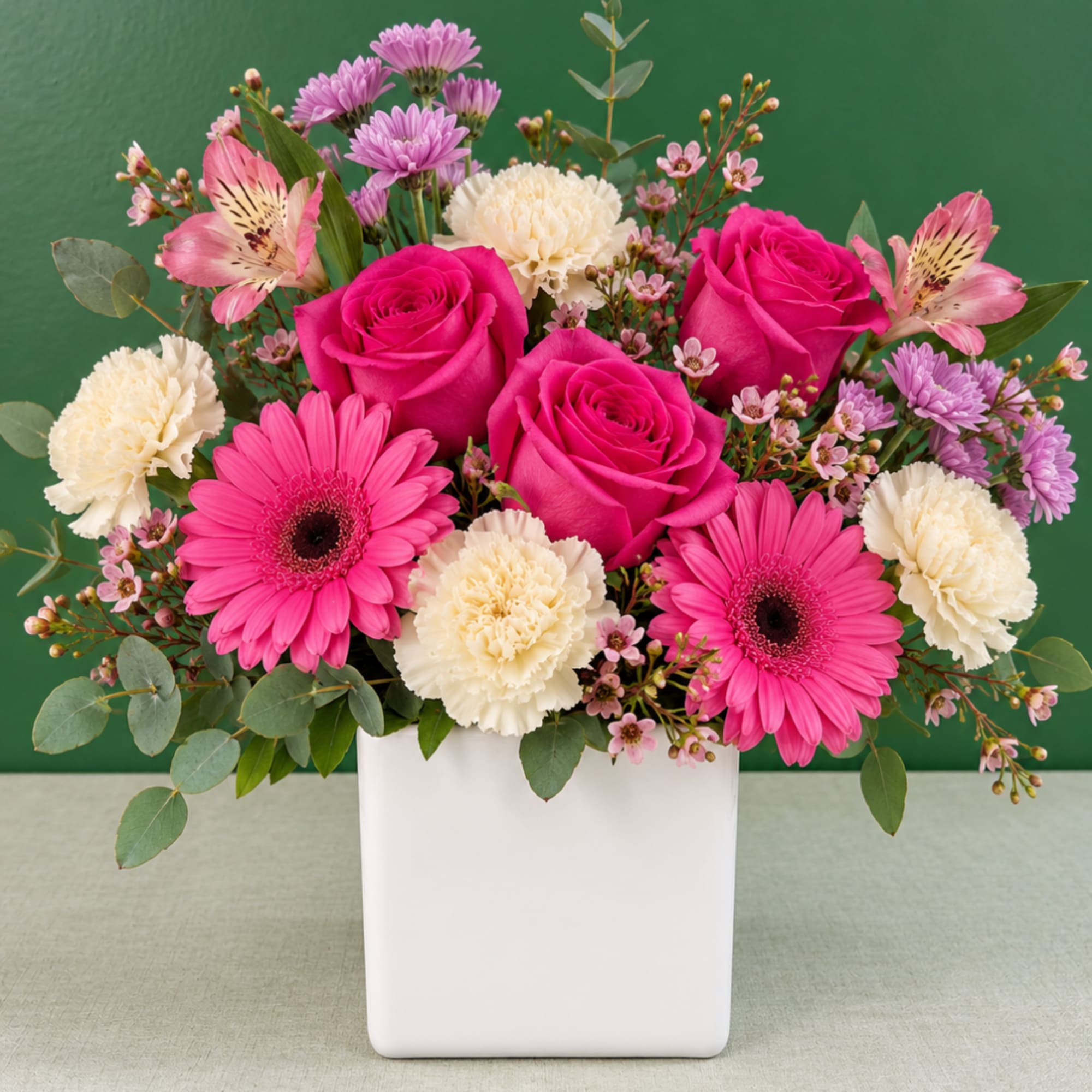 Pink roses, gerbera daisies, and carnations in a white vase