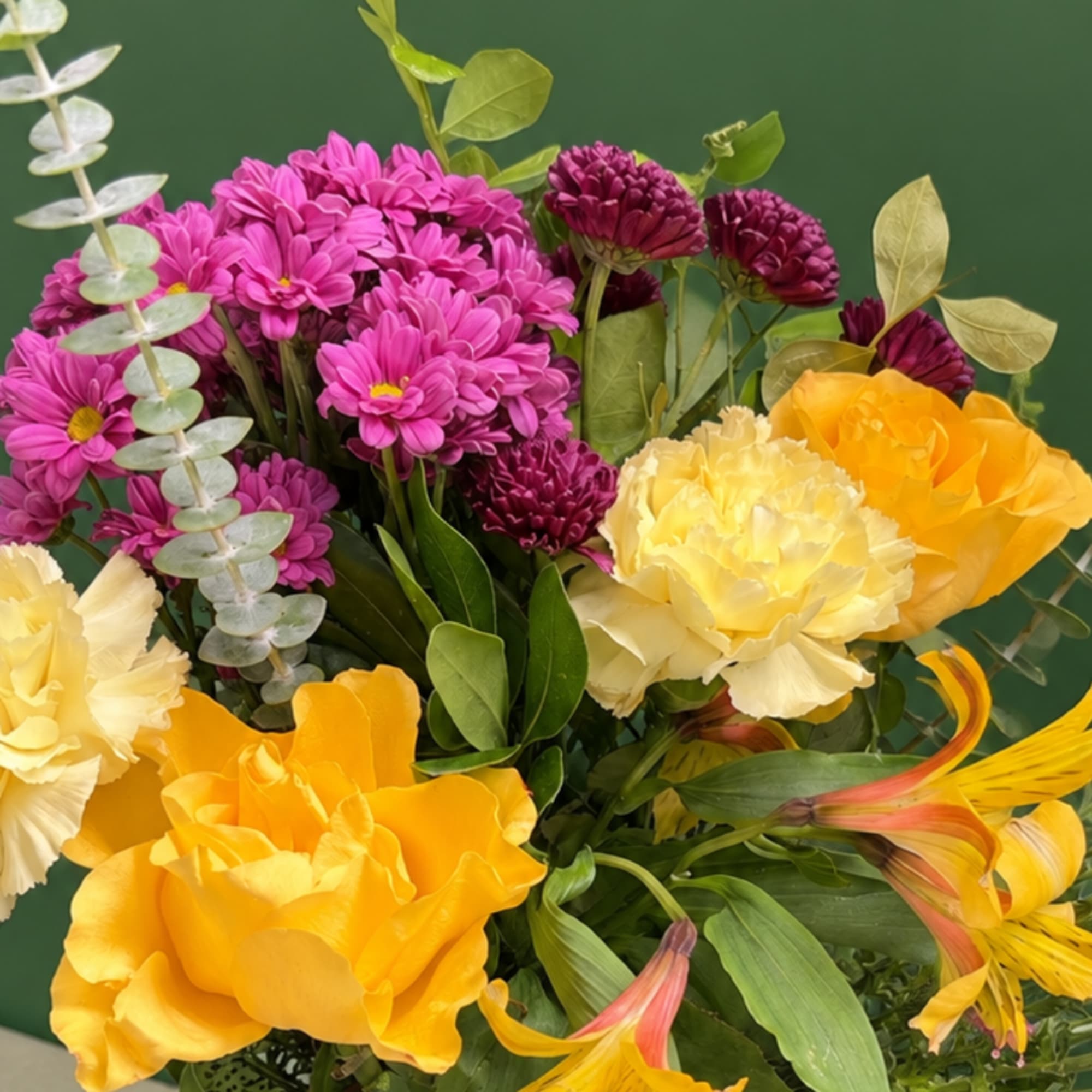 Bouquet of pink daisies, yellow carnations, and orange roses