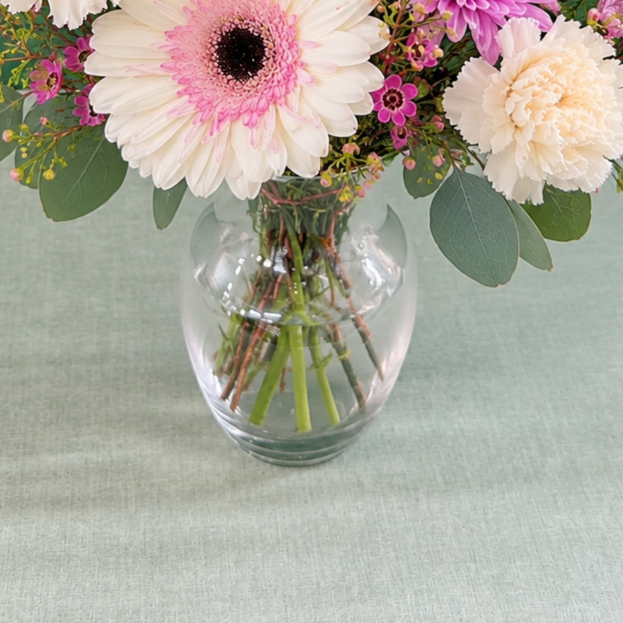 Pink and white flowers arranged in a clear glass vase