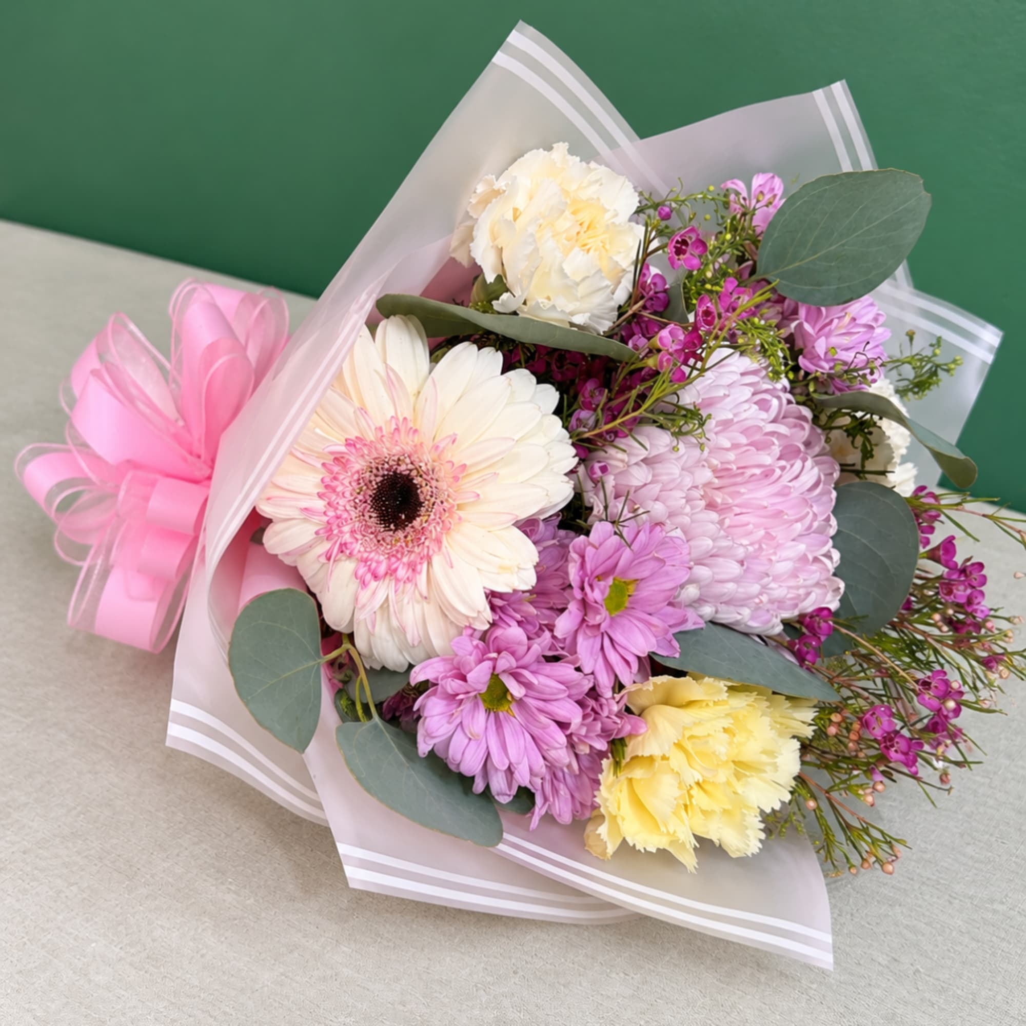 Pink and white mixed bouquet wrapped in translucent paper with a pink bow