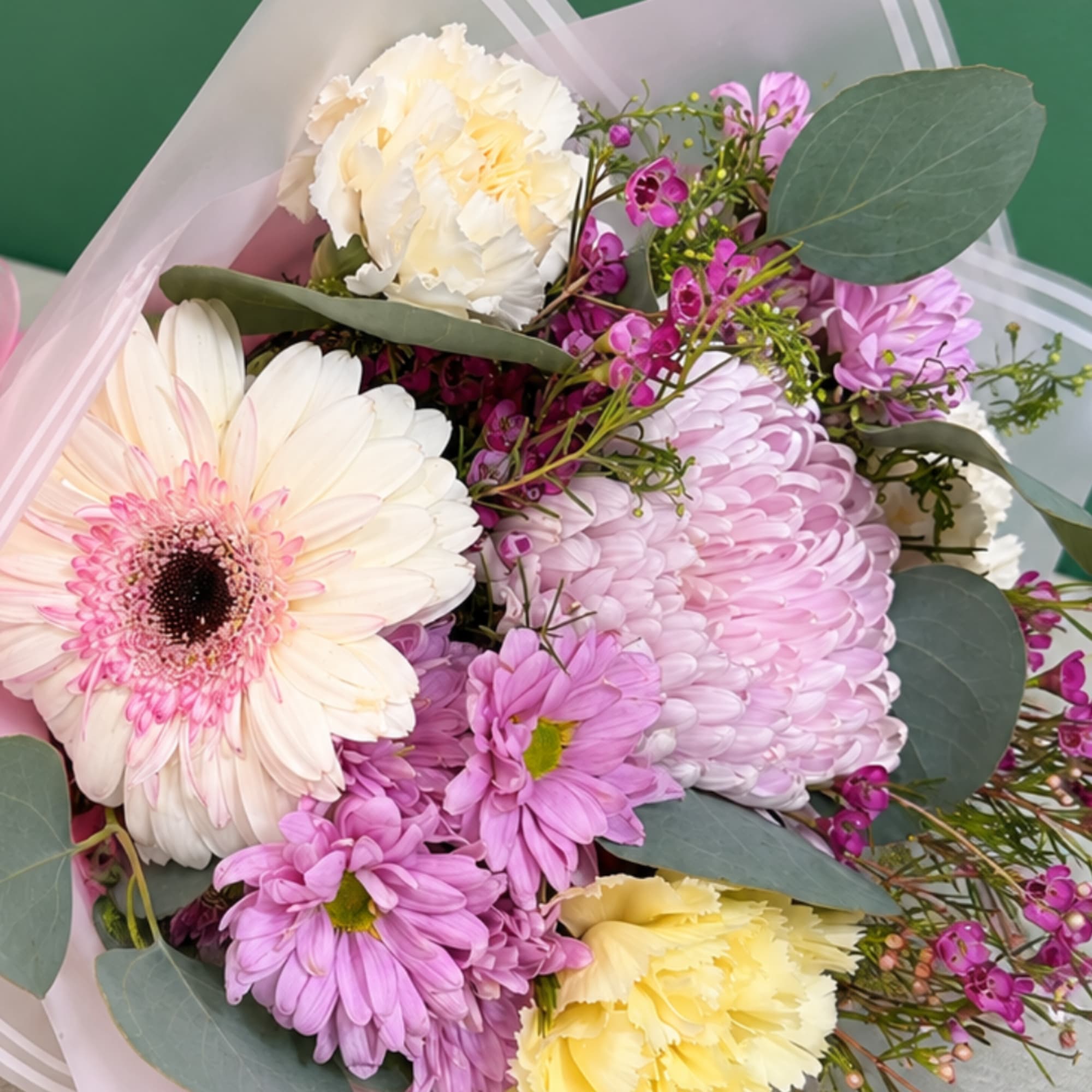 Bouquet of pink and cream flowers wrapped in pale paper