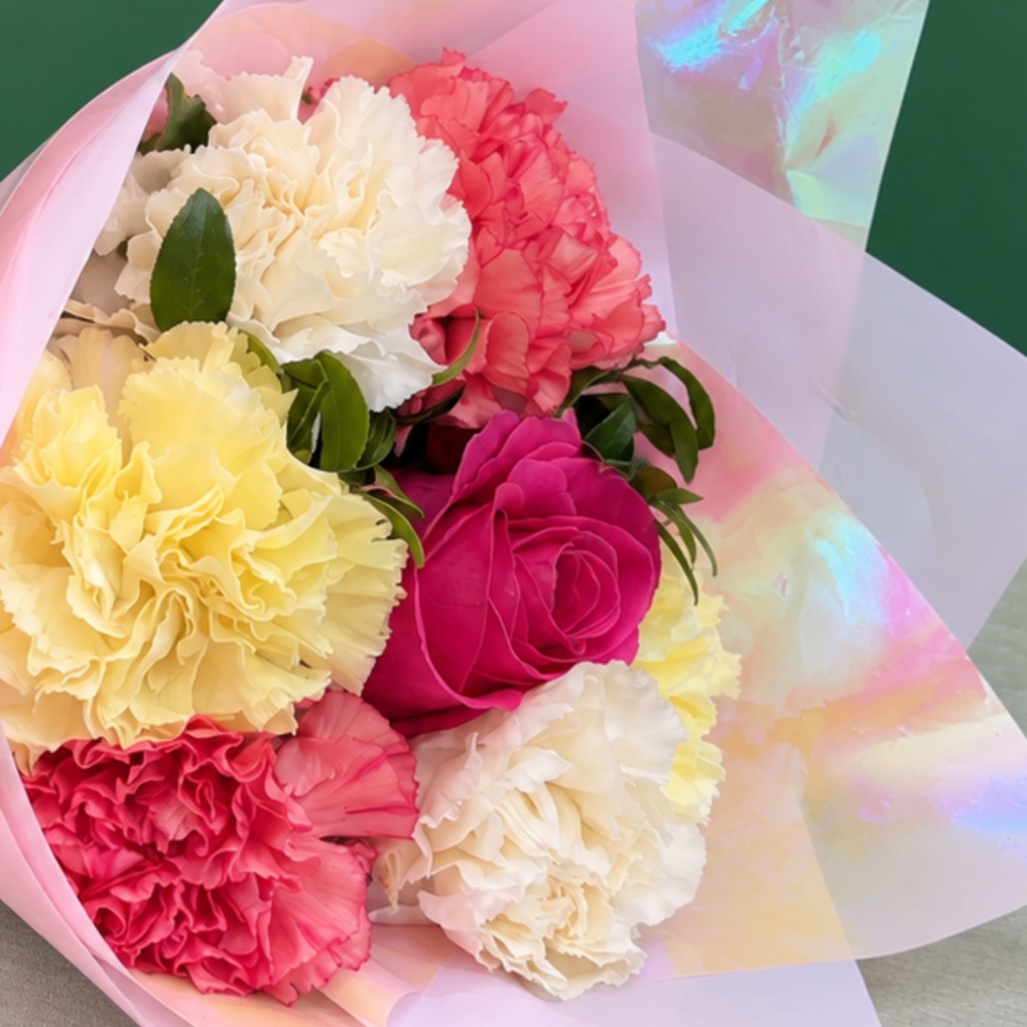 Bouquet of colorful carnations wrapped in pink iridescent paper