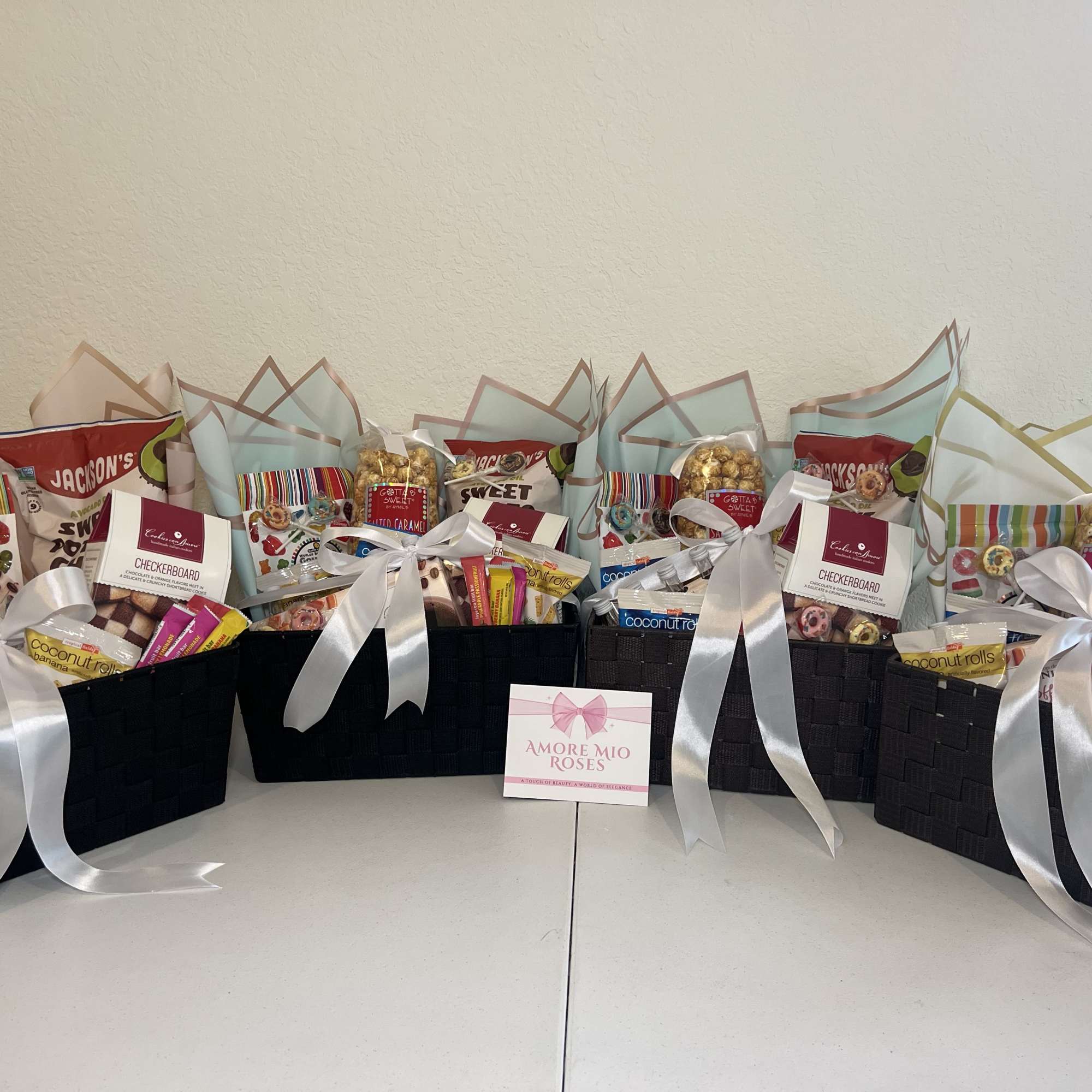 Gift baskets filled with assorted snacks and candy, tied with white ribbons