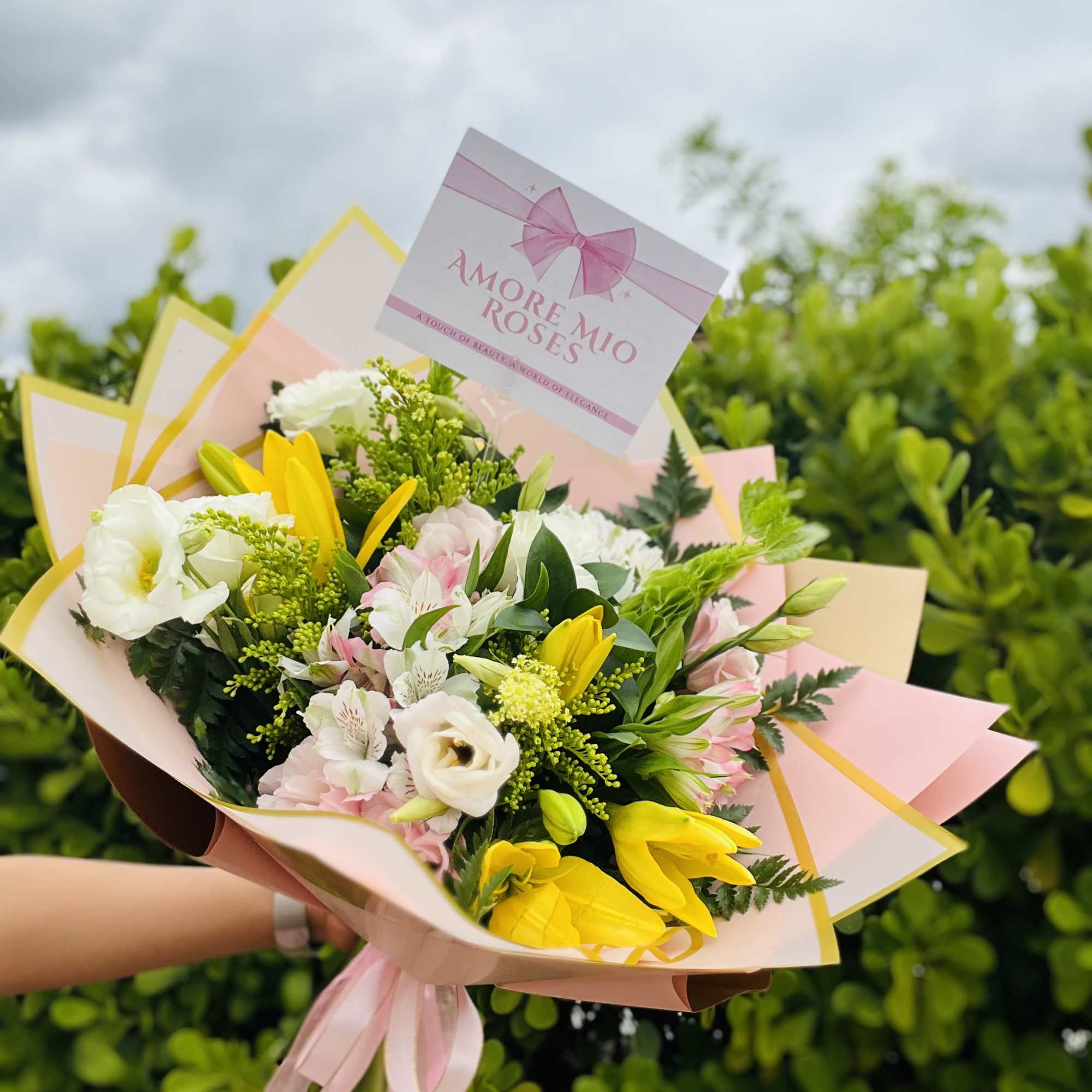 Bouquet of white, pink, and yellow flowers wrapped in pastel paper