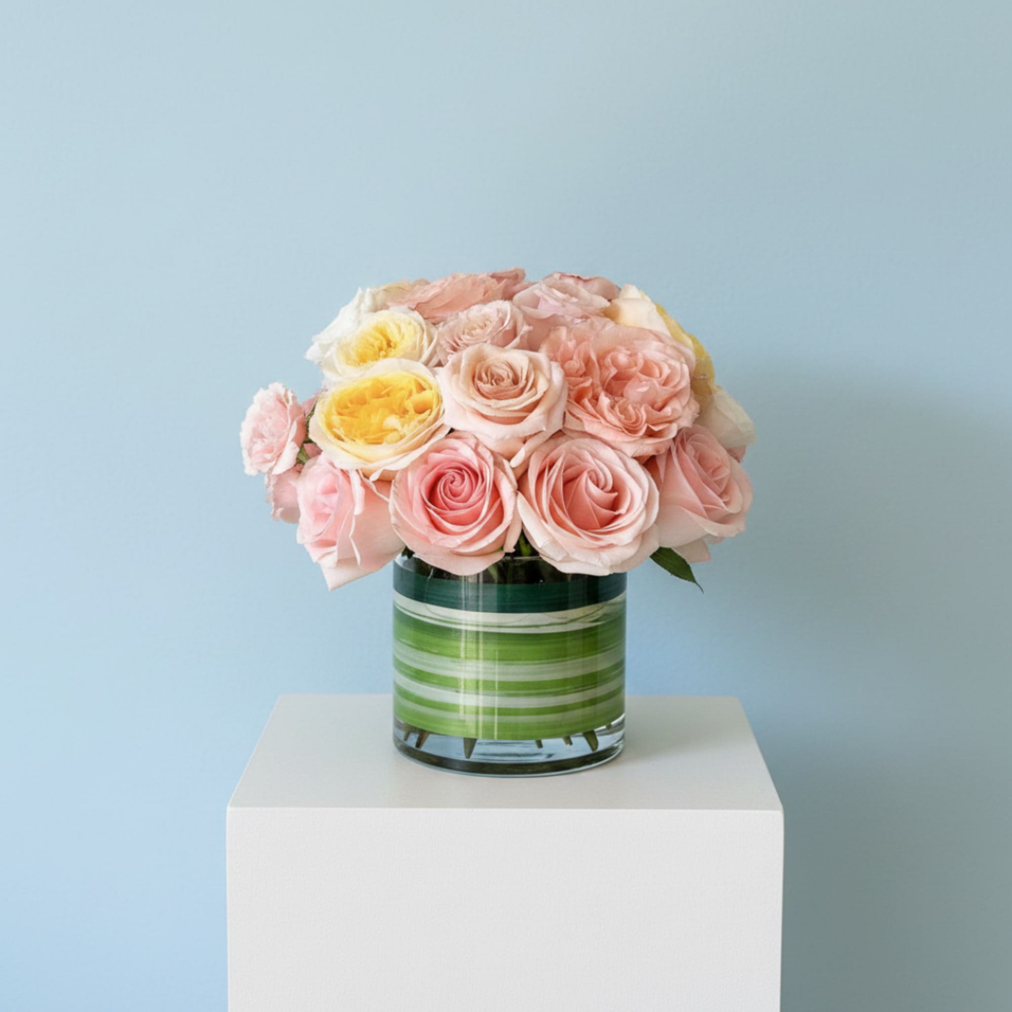 Pink and yellow roses arranged in a striped glass vase, photo 3 of 5