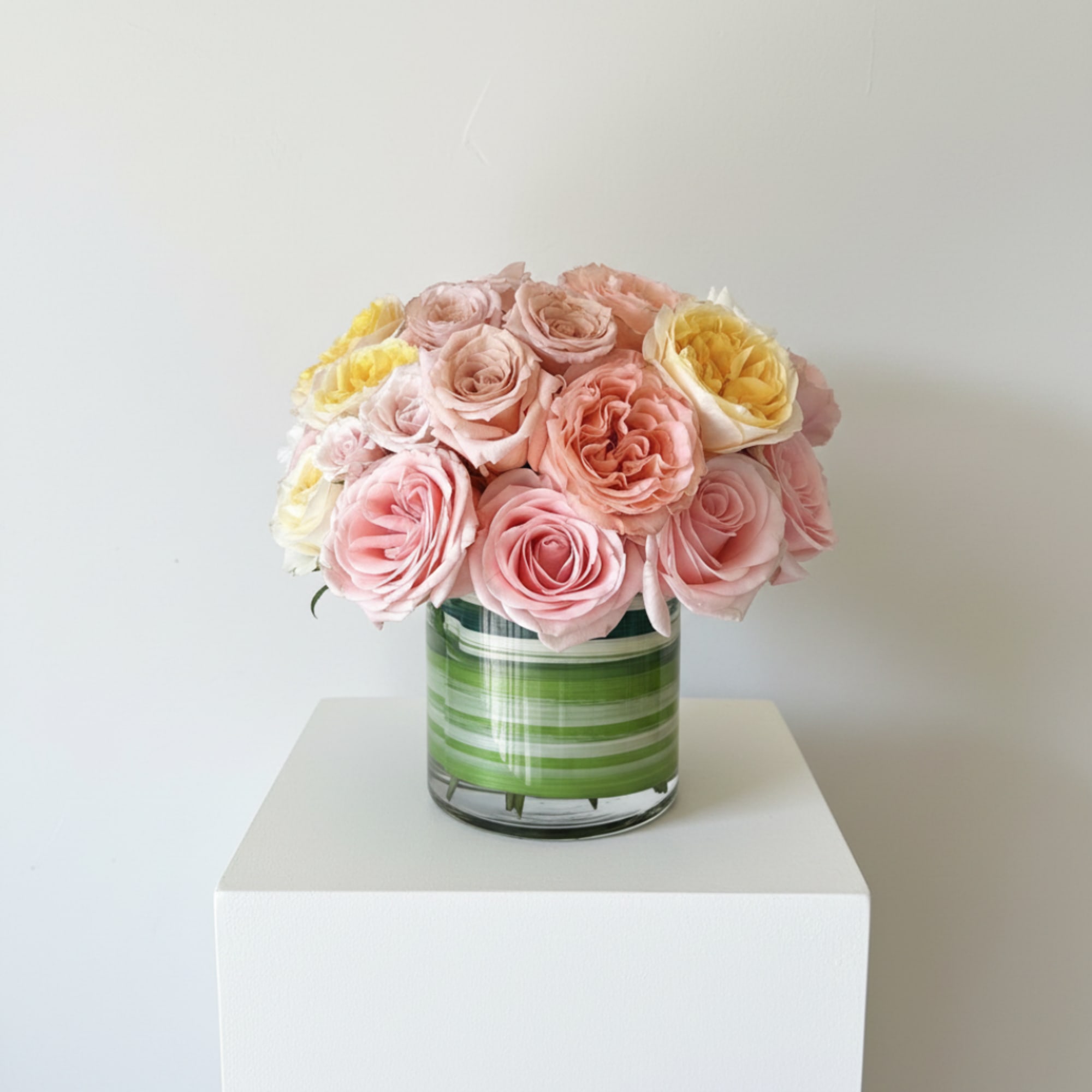 Pink and yellow roses arranged in a striped glass vase, photo 4 of 5