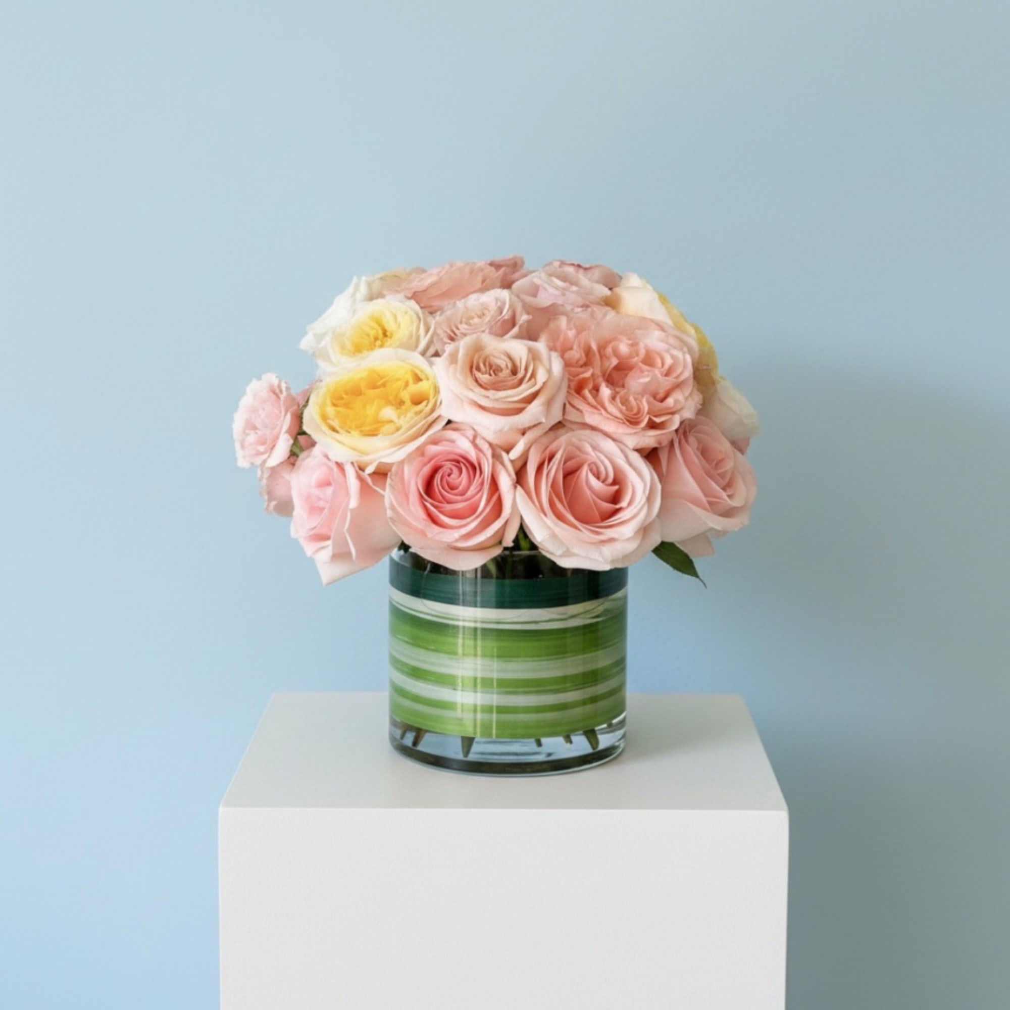 Pink and yellow roses arranged in a striped glass vase, photo 5 of 5