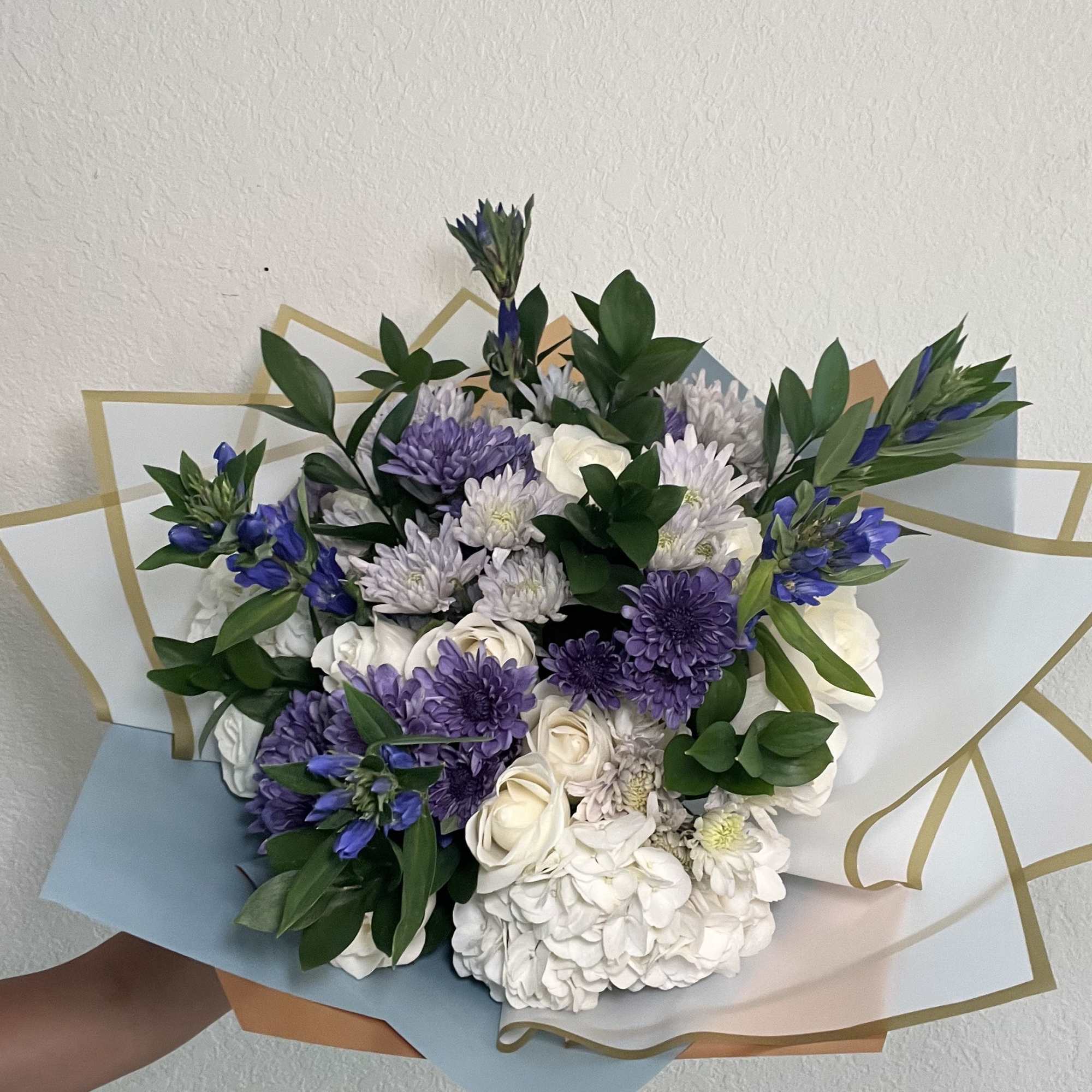 Bouquet of white and purple flowers wrapped in pastel paper