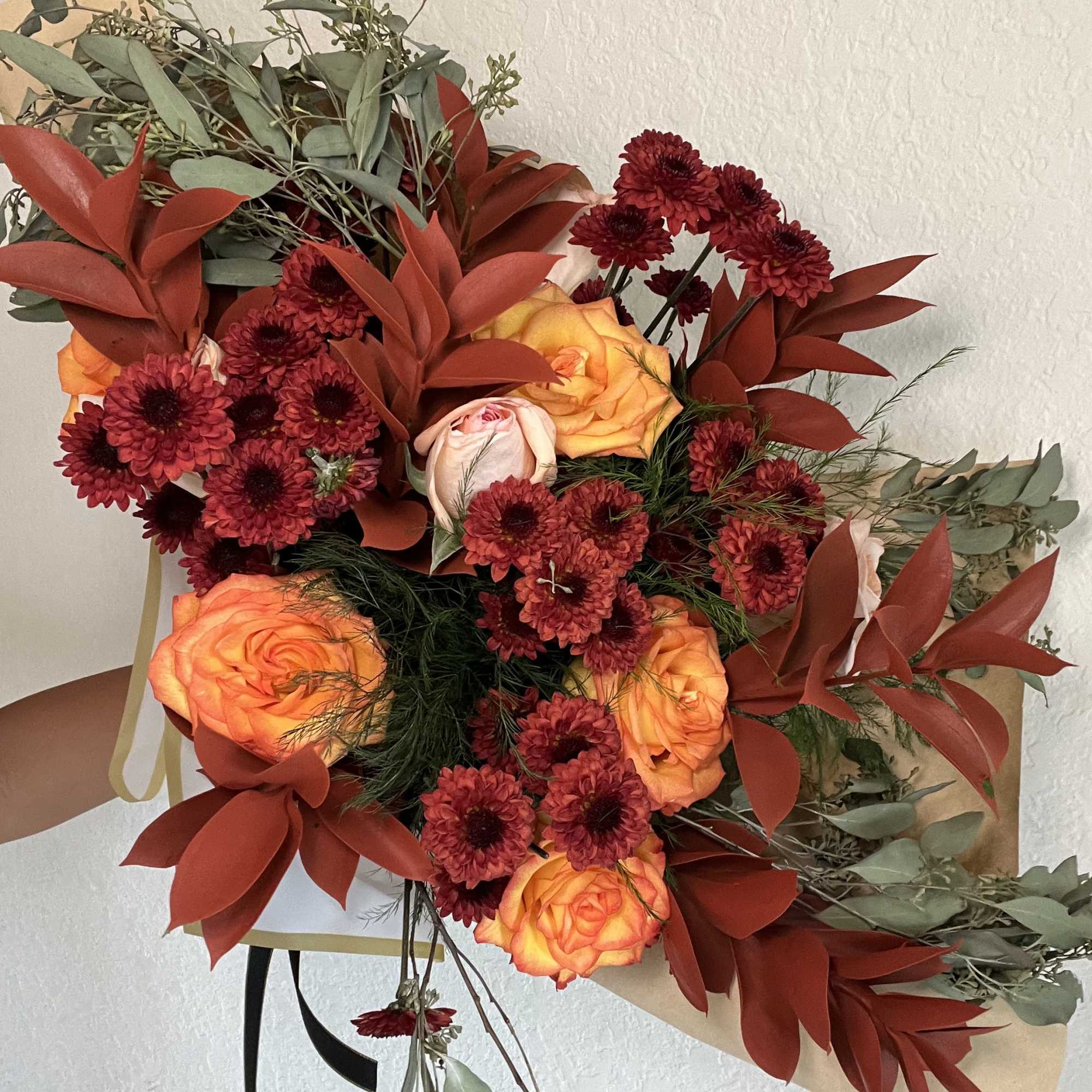 Bouquet of orange roses and burgundy mums with dried foliage