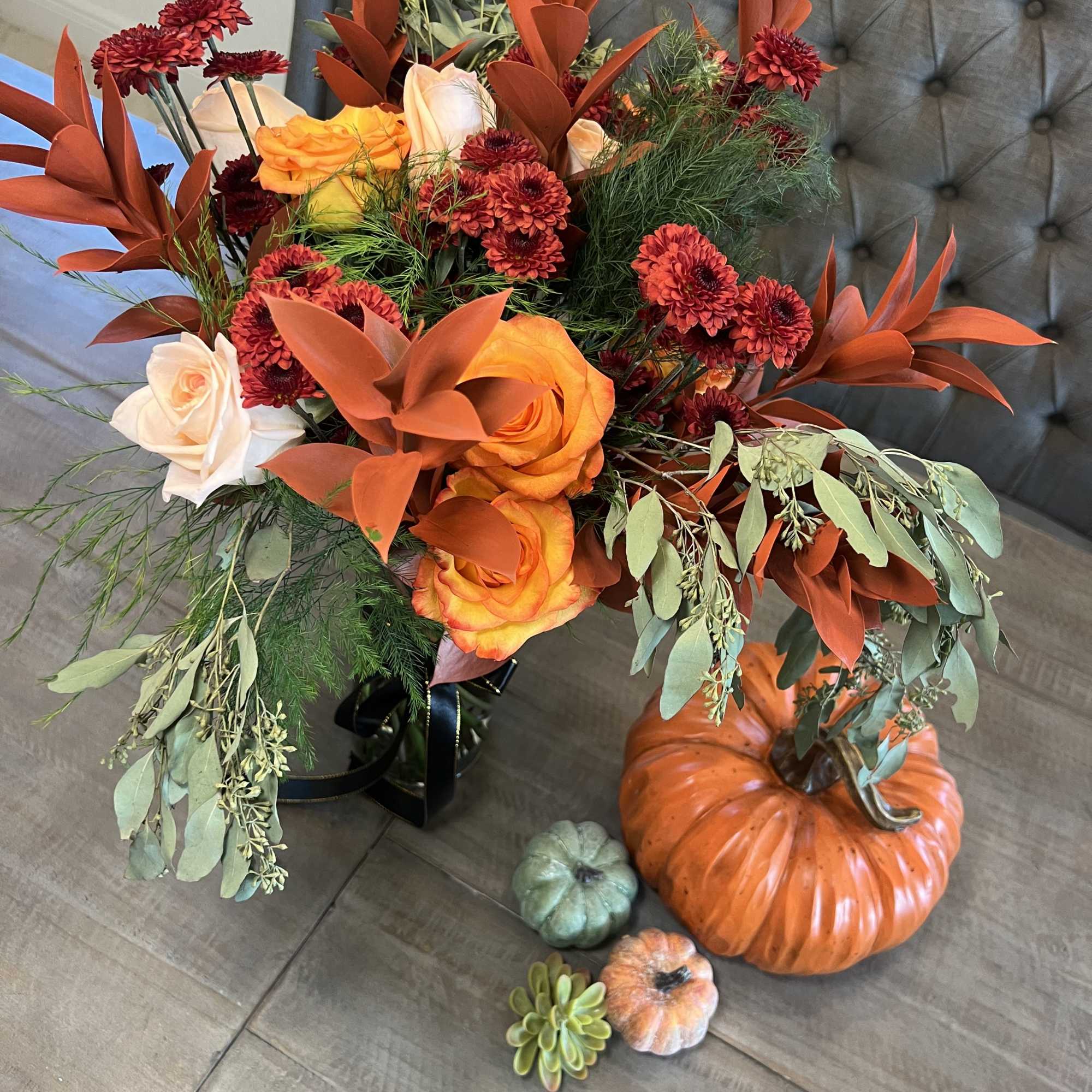 Autumn bouquet with orange roses and red mums in a black vase