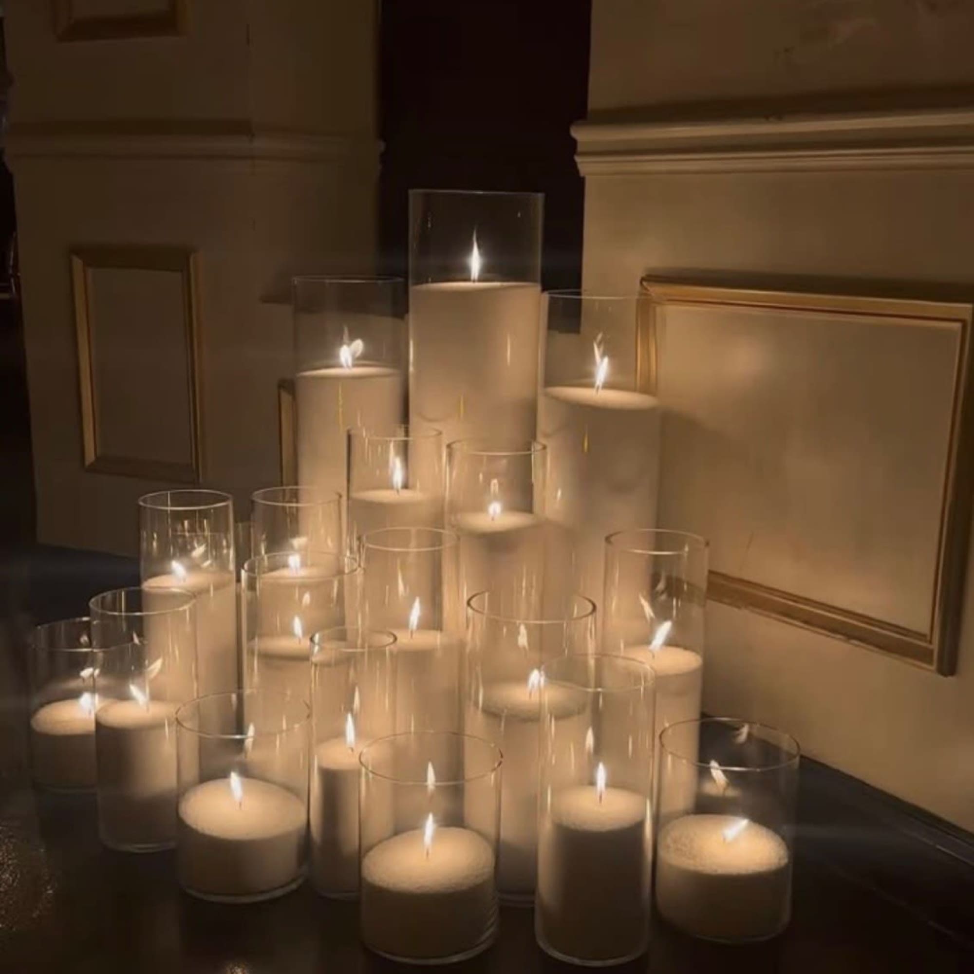 Cluster of lit white pillar candles in clear glass cylinders