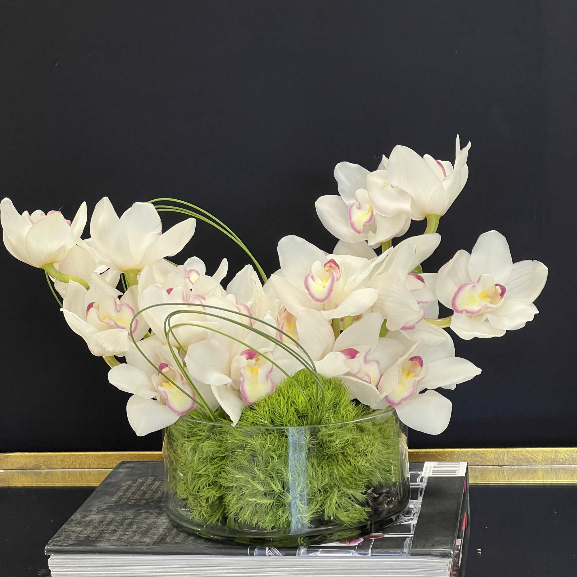 White orchids arranged in a glass bowl with green moss