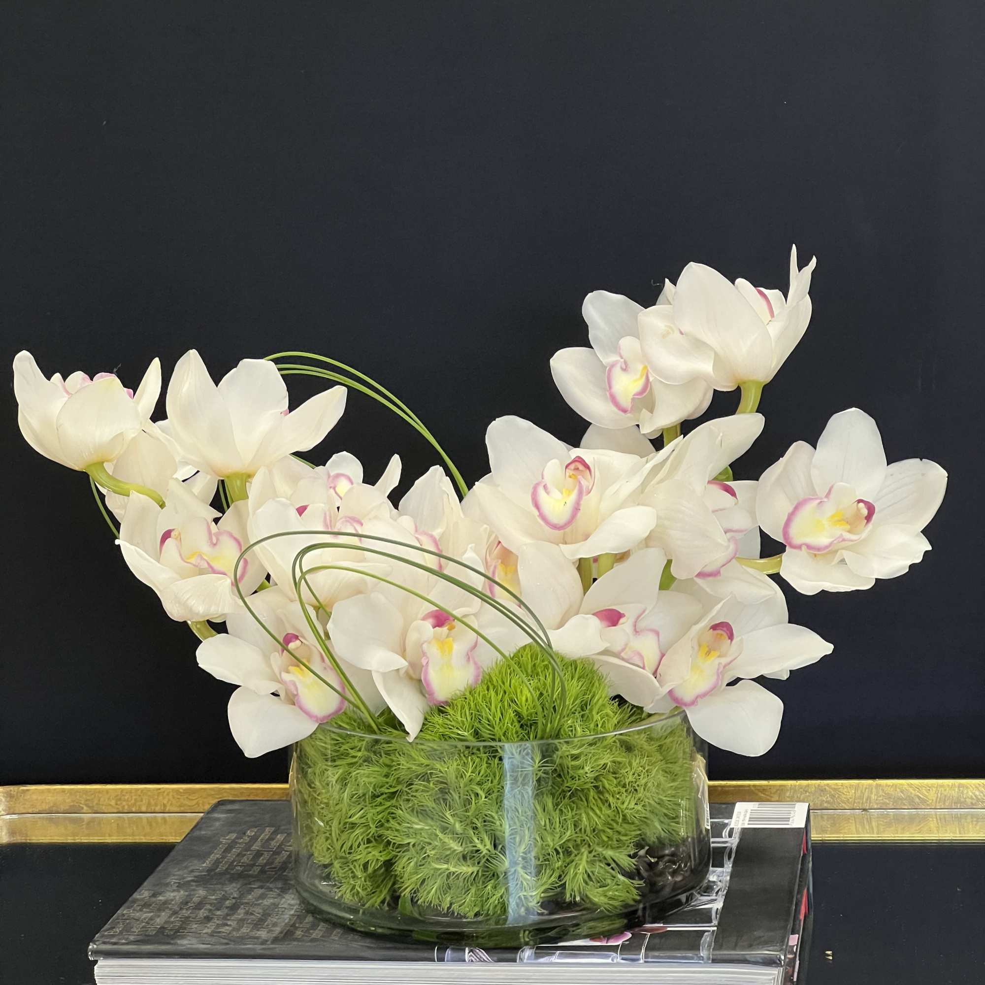White orchids in a glass bowl with bright green moss