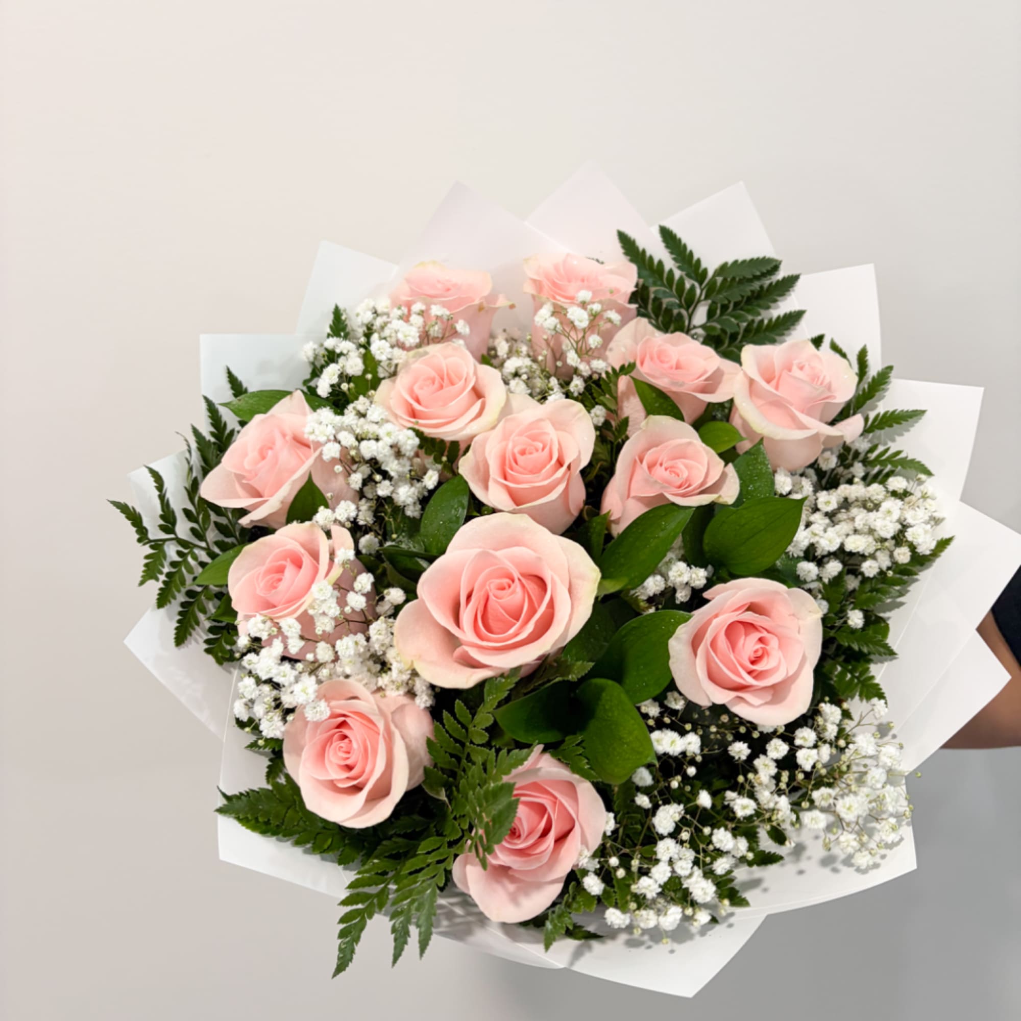 Bouquet of pale pink roses with white baby's breath and white wrapping
