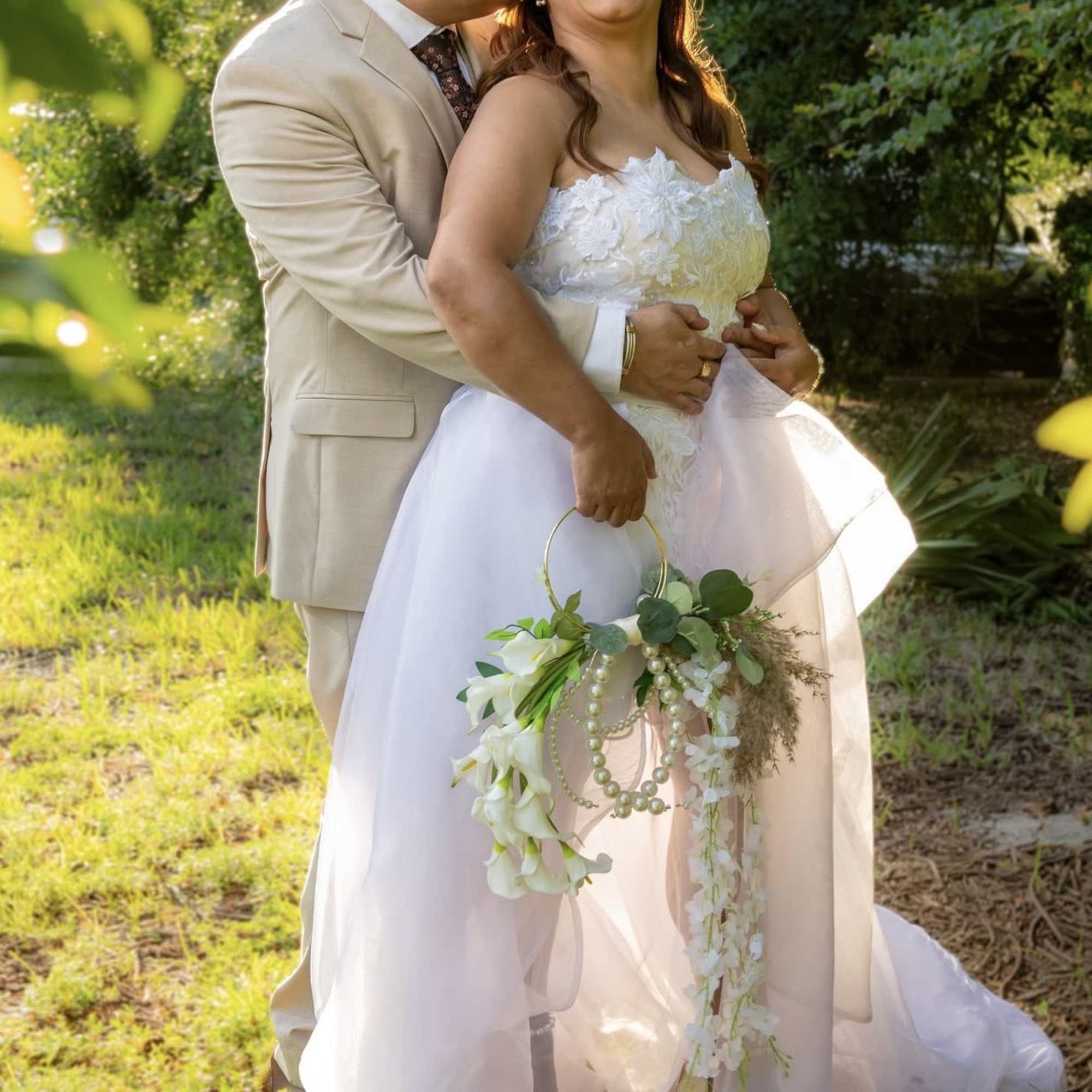 Bride and groom holding a white floral bouquet with a hoop handle