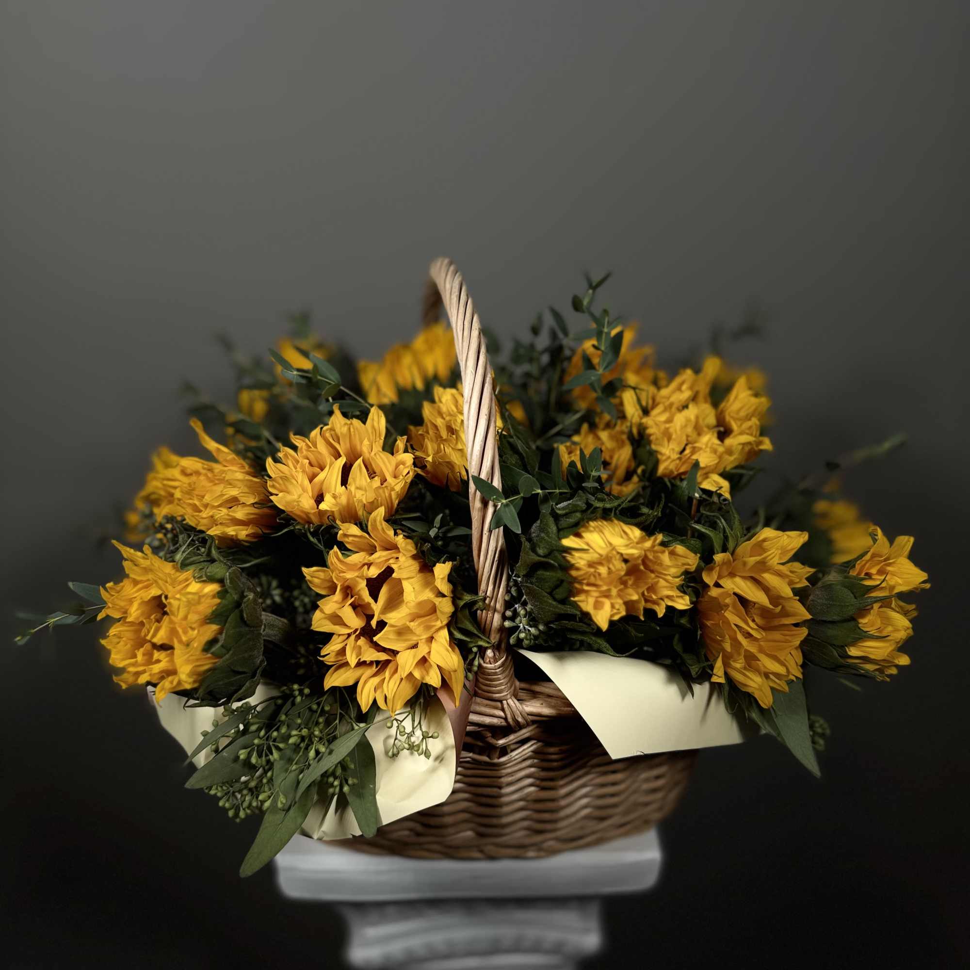 Yellow flowers arranged in a wicker basket with a handle